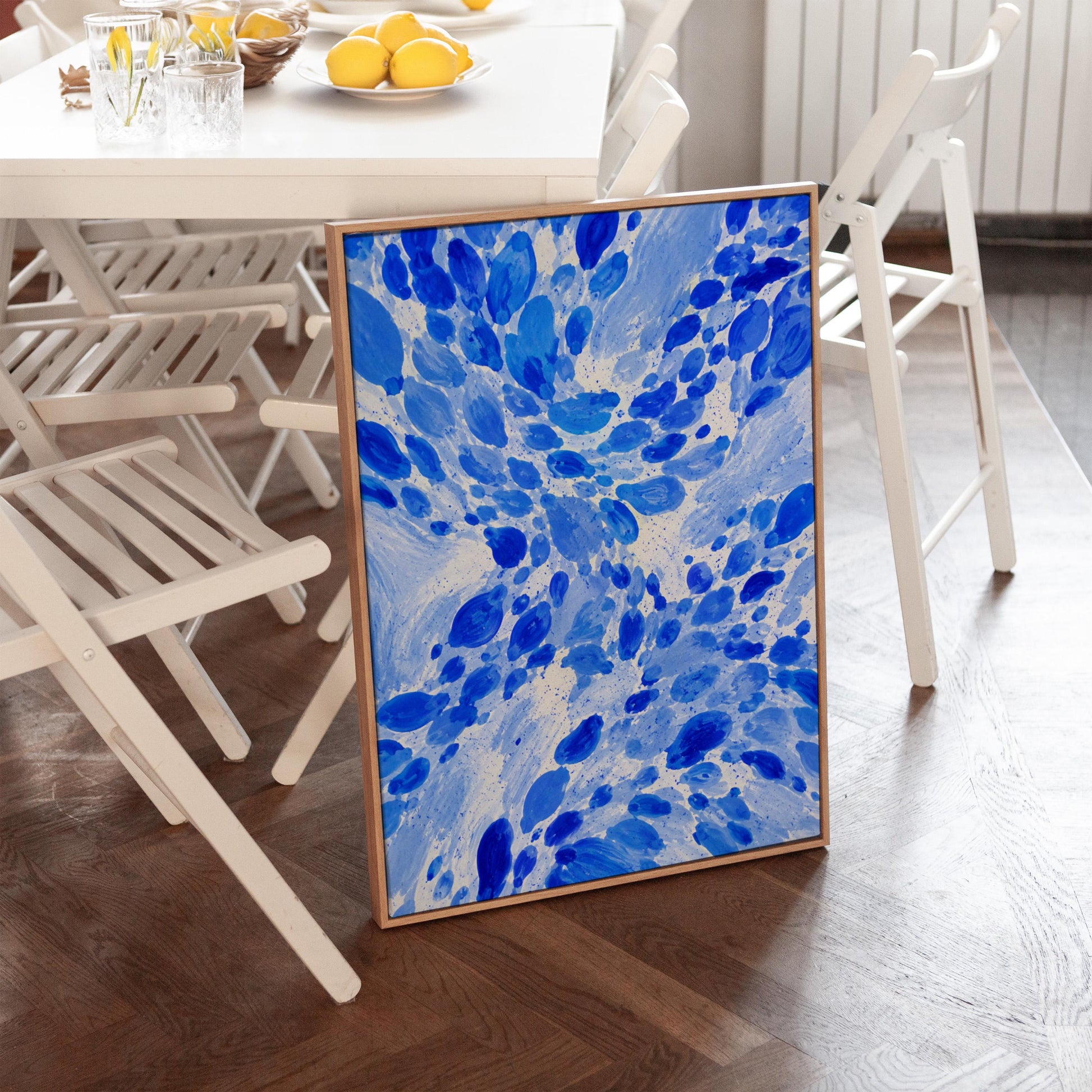 Burst of cobalt blue droplets scattering across pale background, canvas wall art hanging in a calm, modern living space