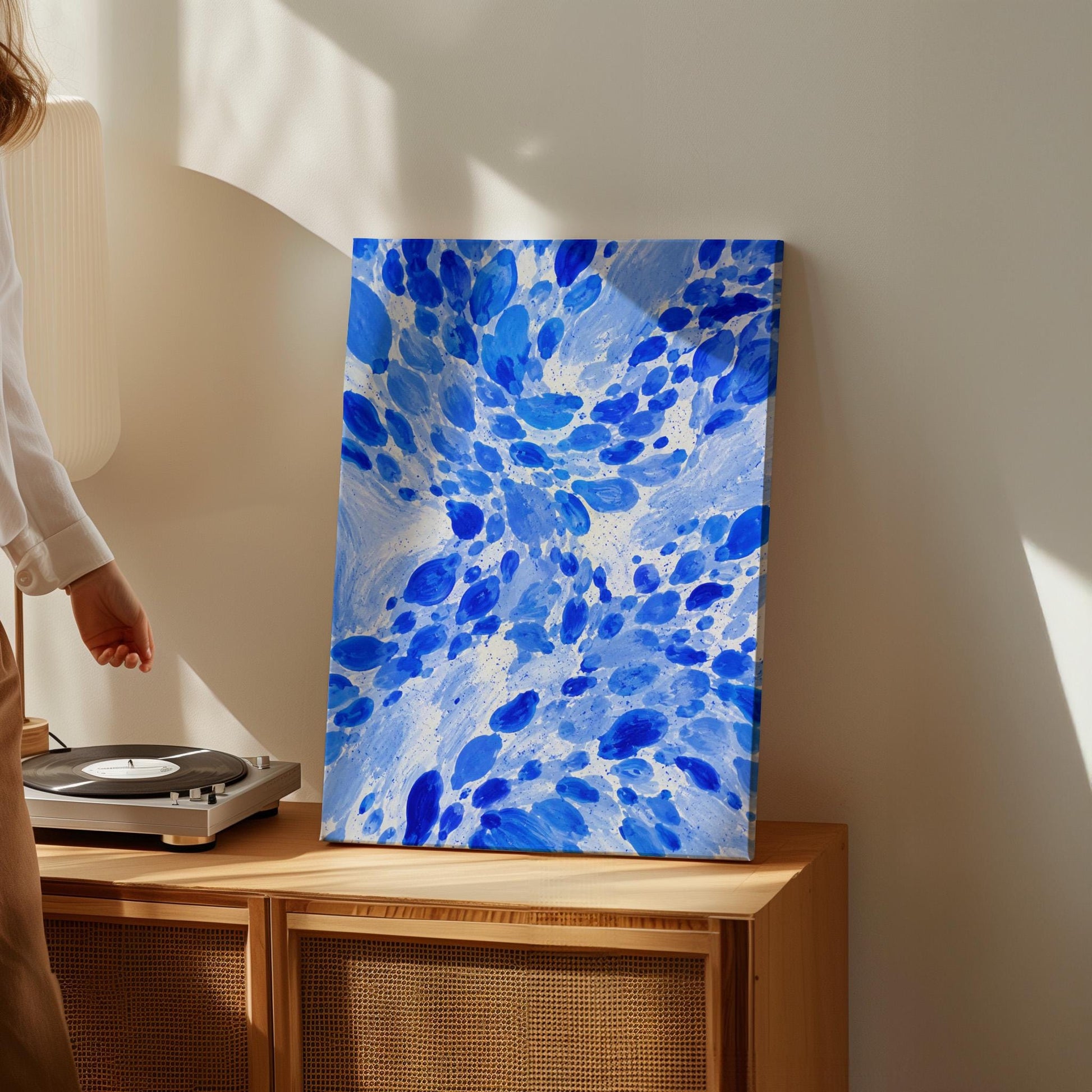 Burst of cobalt blue droplets scattering across pale background, canvas wall art on a quiet wall in a considered interior