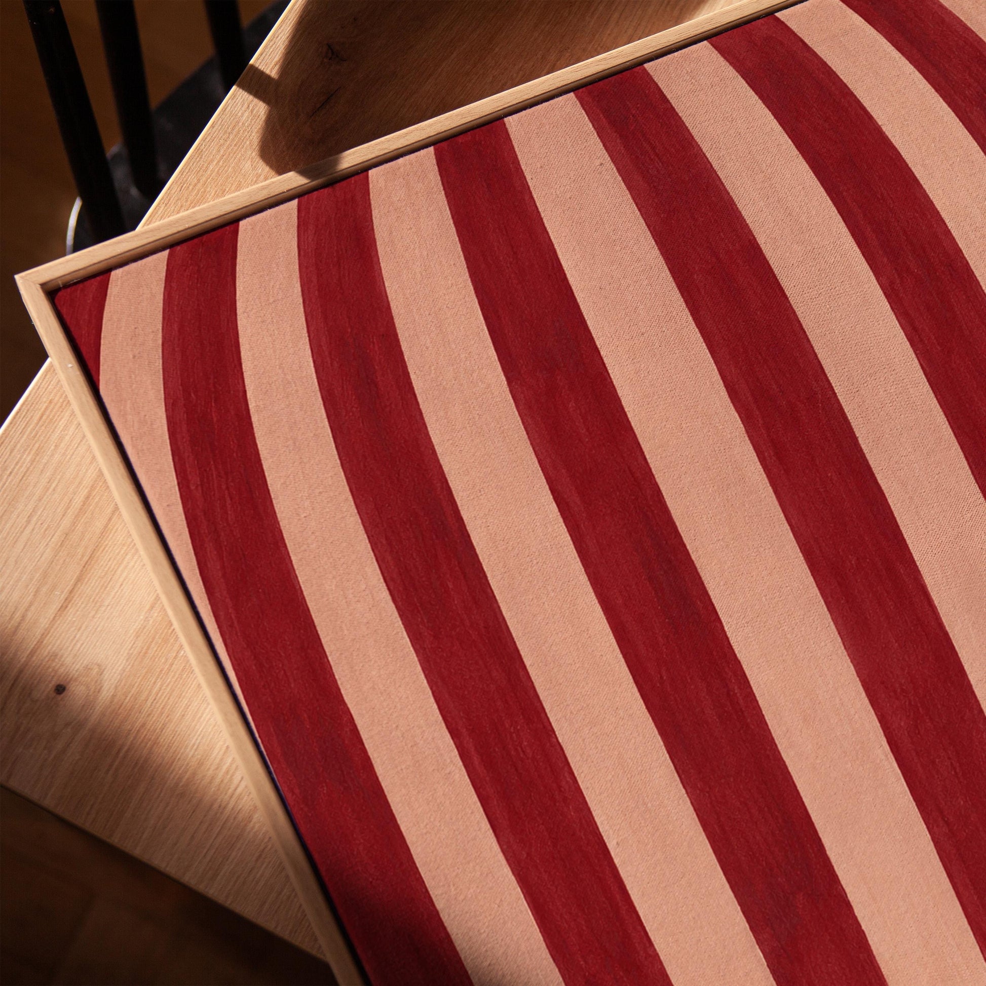 Curved burgundy stripes bowing over blush background, canvas print in a warm, minimally styled interior