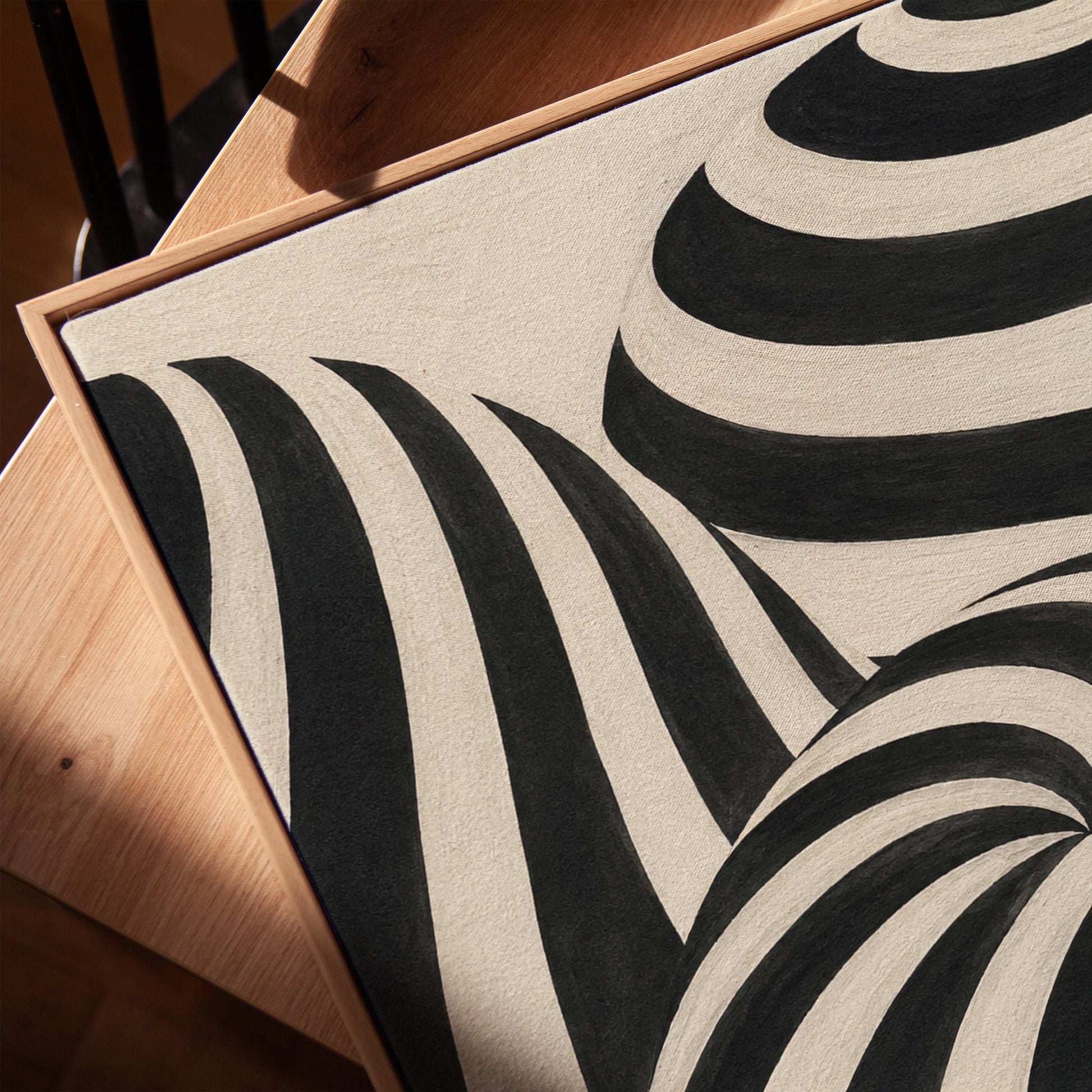 Swirling black and white striped forms, canvas print in a warm, minimally styled interior