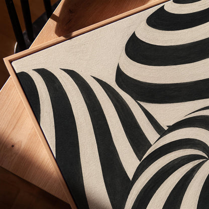 Swirling black and white striped forms, canvas print in a warm, minimally styled interior