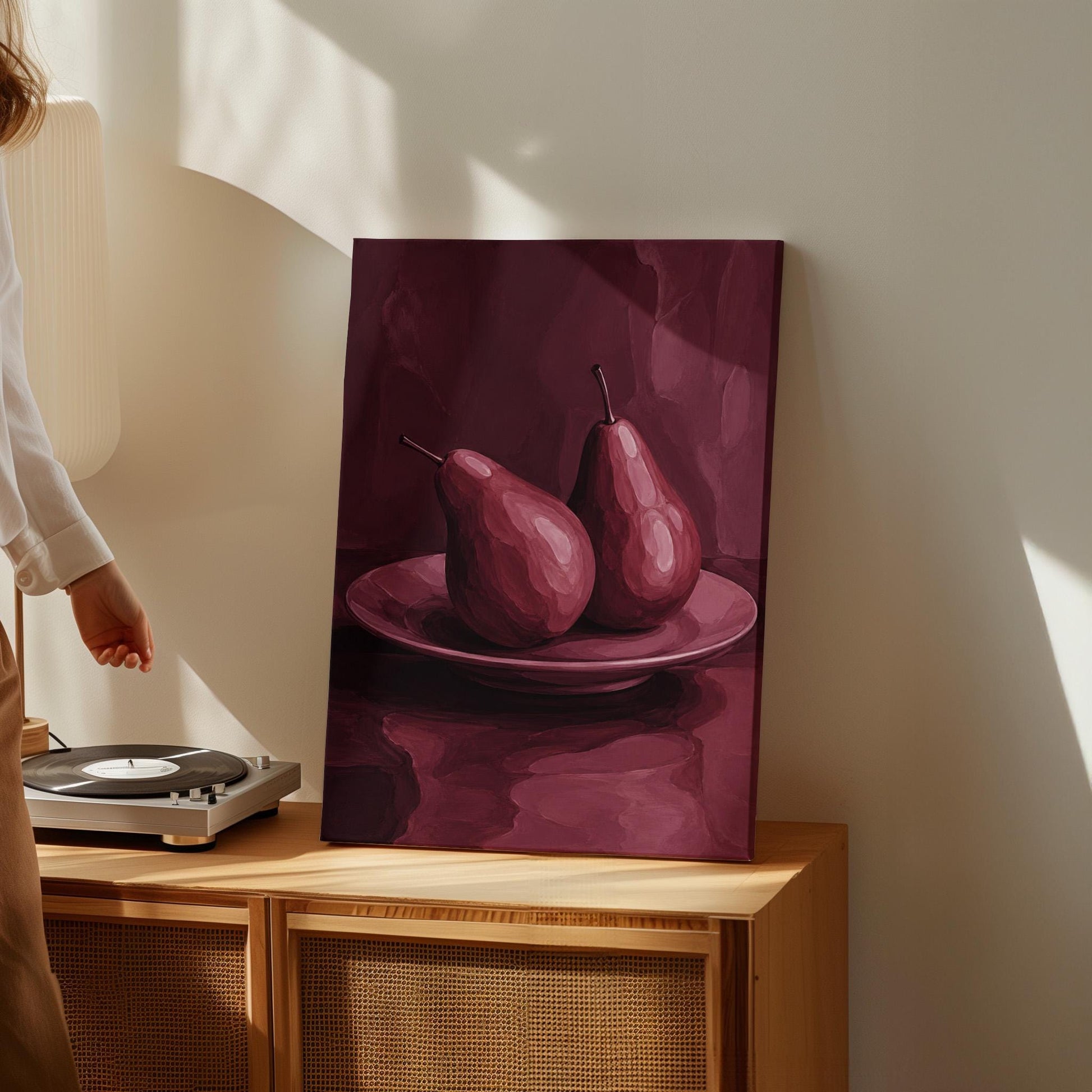 Two pears on a plate painted in burgundy monochrome, canvas print presented in a light, minimal room