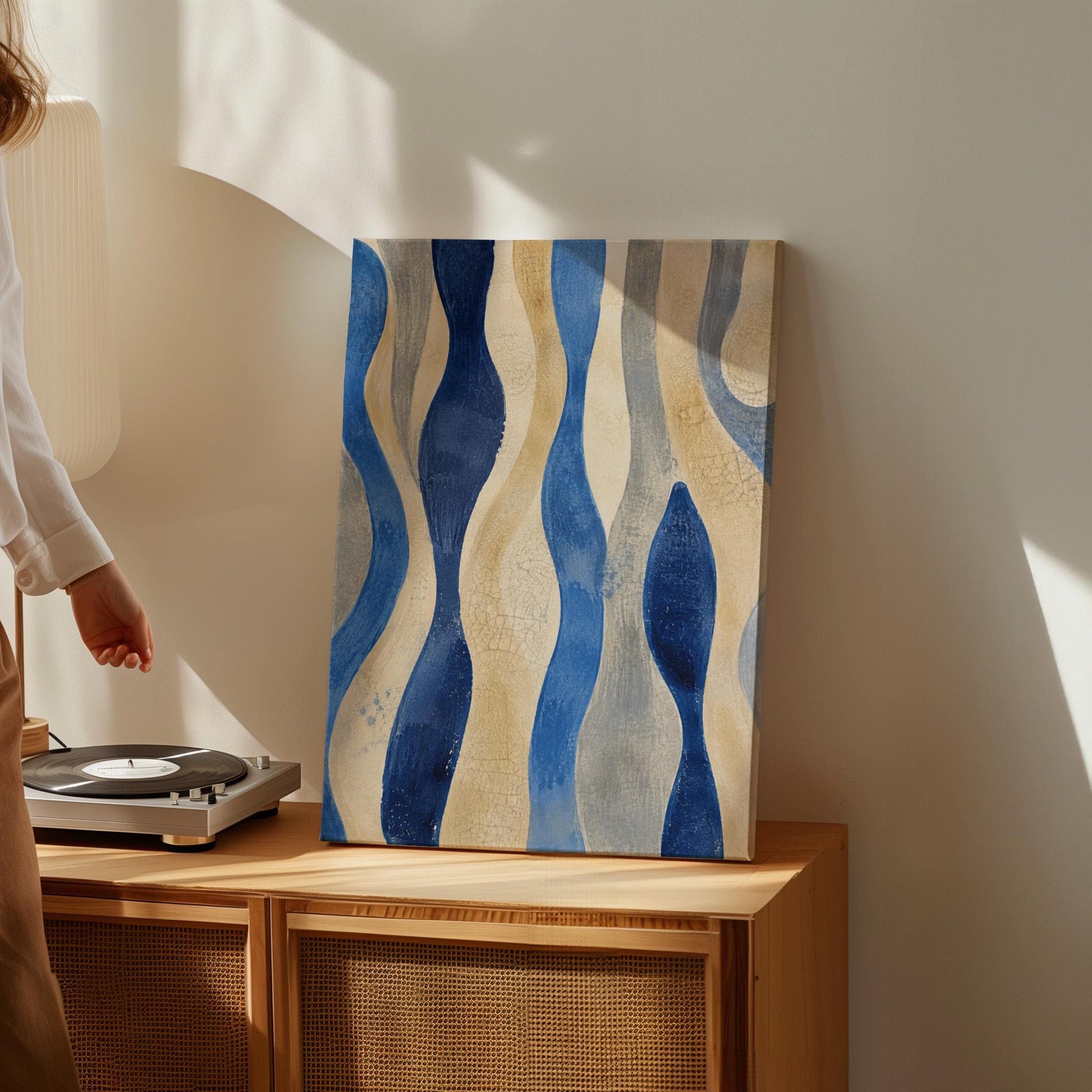Vertical flowing wave bands in indigo and cream, canvas print presented in a light, minimal room