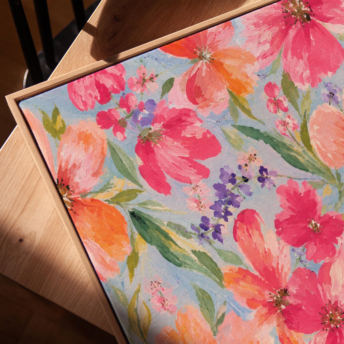 Vivid pink and purple watercolor blooms on light blue, canvas print in a warm, minimally styled interior
