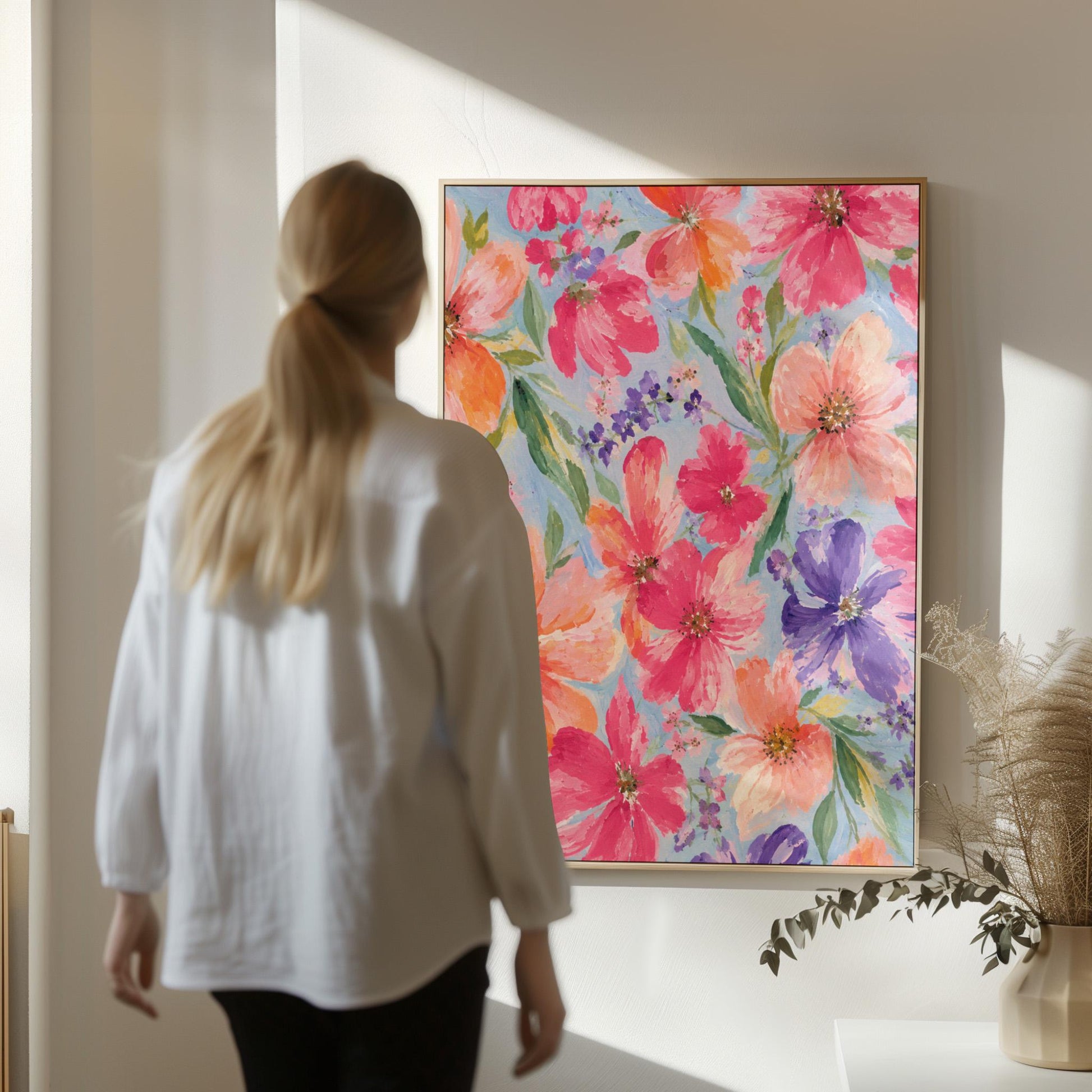 Vivid pink and purple watercolor blooms on light blue, canvas print displayed on a neutral wall in a styled interior