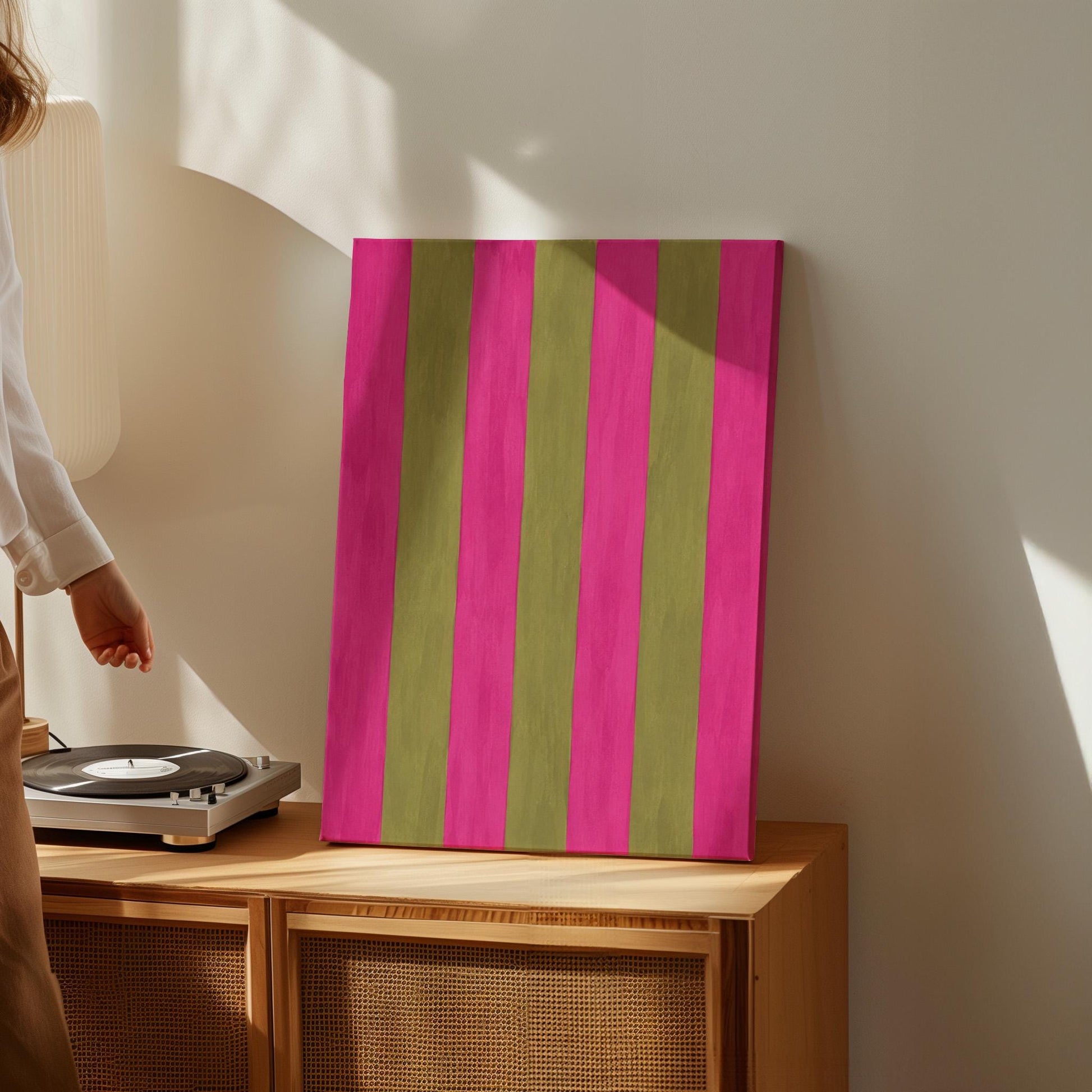 Bold vertical stripes in hot pink and olive green, canvas print styled against a soft white wall