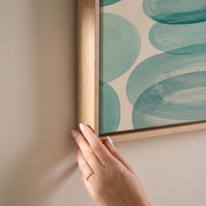 Overlapping aqua rings rolling across horizontal frame, canvas print shown at full size in a light-filled bedroom
