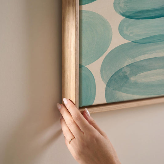 Overlapping aqua rings rolling across horizontal frame, canvas print shown at full size in a light-filled bedroom