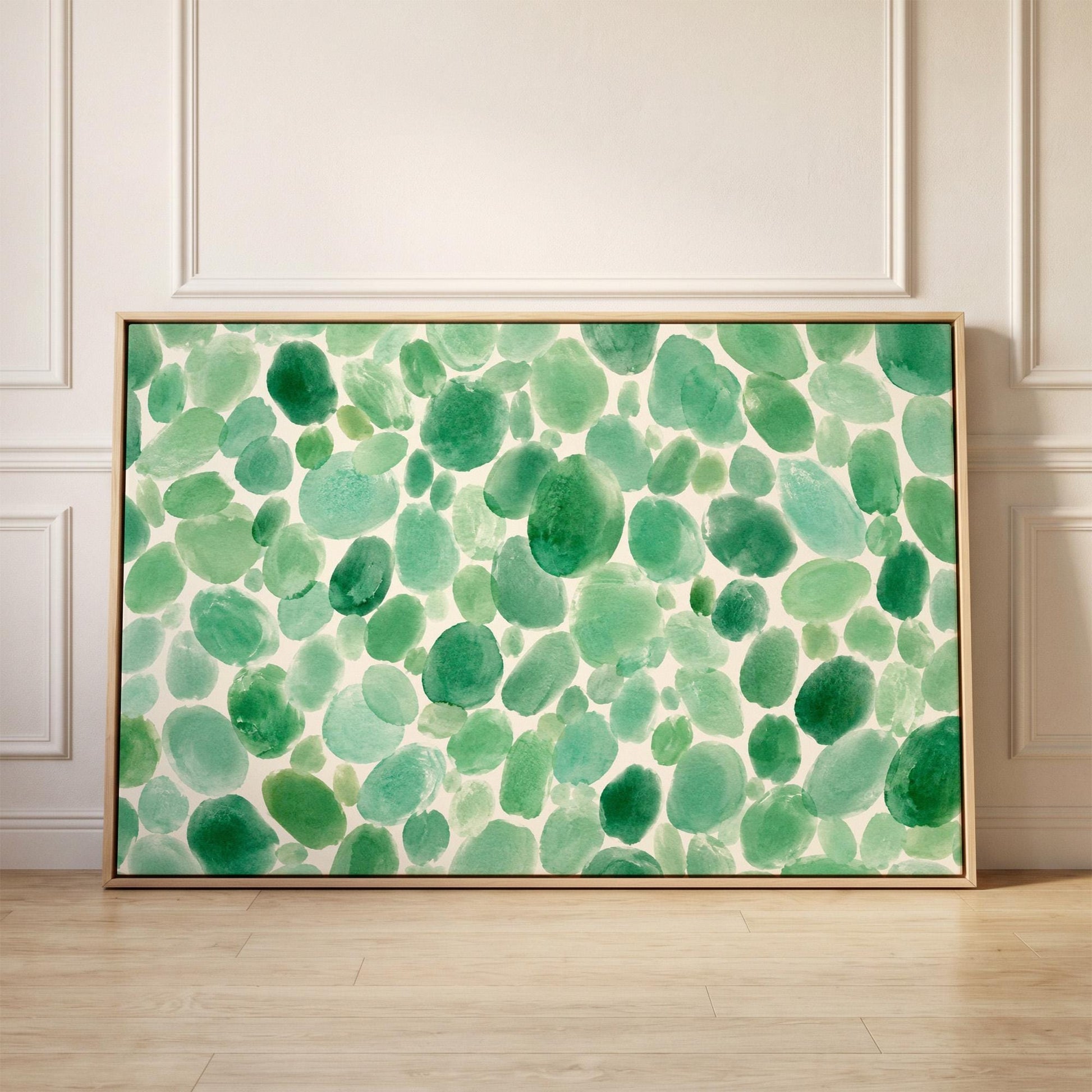 Field of green watercolor pebbles spread wide, canvas print held up against a sunlit bedroom wall
