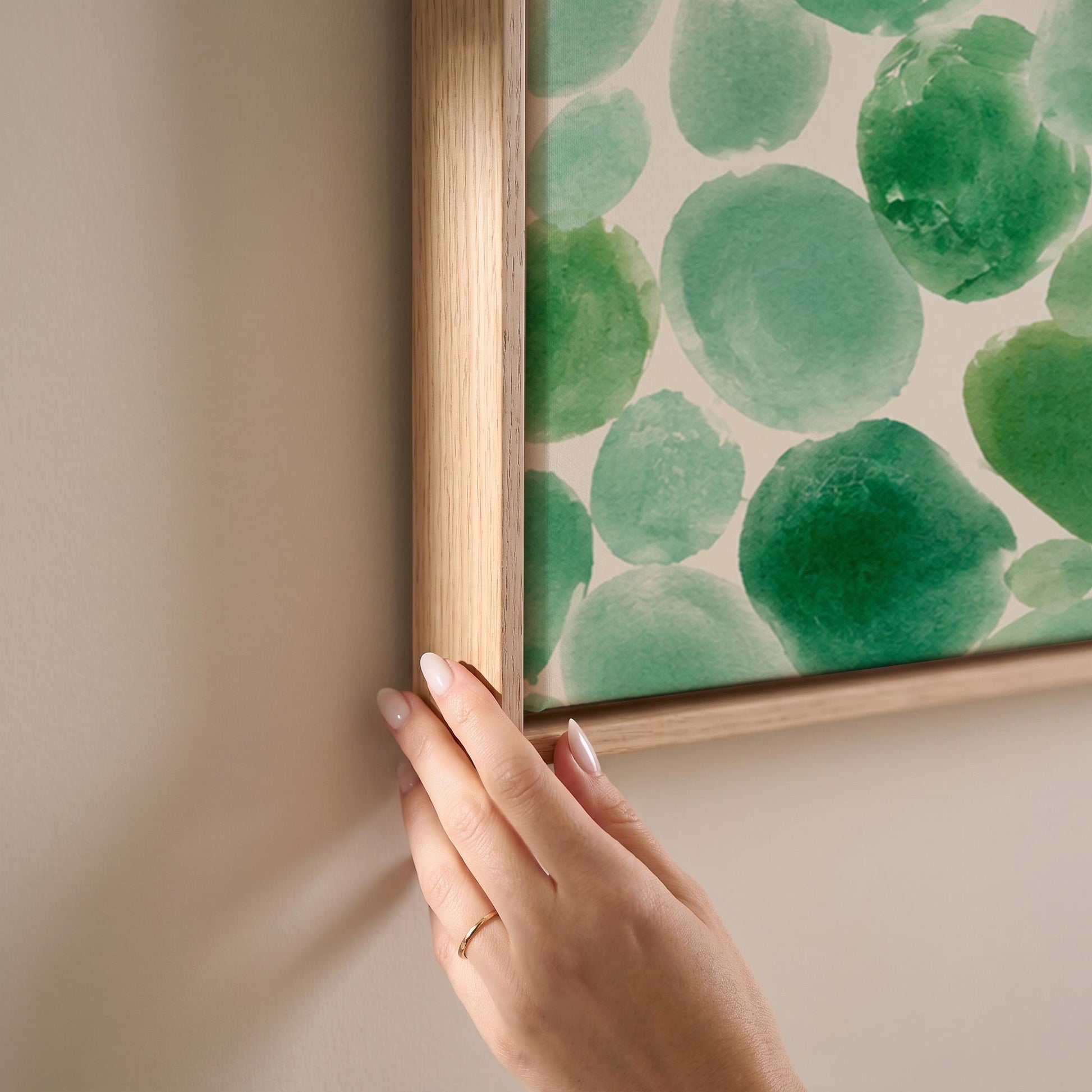 Field of green watercolor pebbles spread wide, canvas print shown at full size in a light-filled bedroom