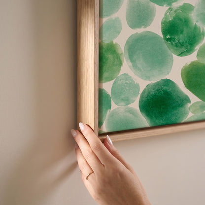Field of green watercolor pebbles spread wide, canvas print shown at full size in a light-filled bedroom