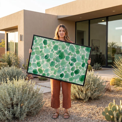 Field of green watercolor pebbles spread wide, canvas print shown to scale in a furnished room