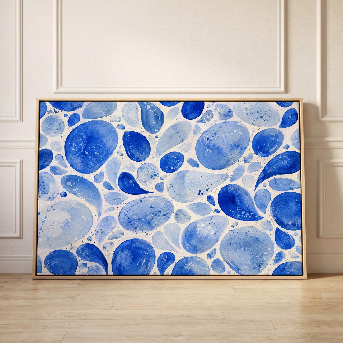 Watercolor blue pebbles spread across wide frame, canvas print held up against a sunlit bedroom wall