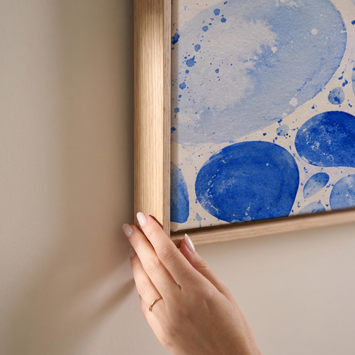 Watercolor blue pebbles spread across wide frame, canvas print shown at full size in a light-filled bedroom