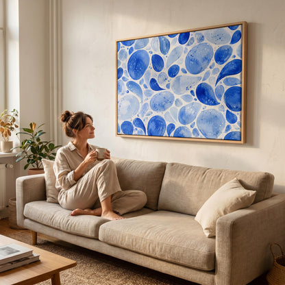 Watercolor blue pebbles spread across wide frame, canvas print on a quiet wall in a considered interior