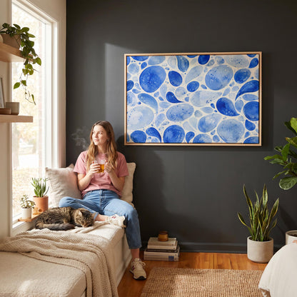 Watercolor blue pebbles spread across wide frame, canvas print shown in a sunlit, contemporary room