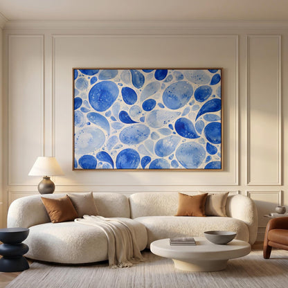 Watercolor blue pebbles spread across wide frame, canvas wall art hanging in a calm, modern living space