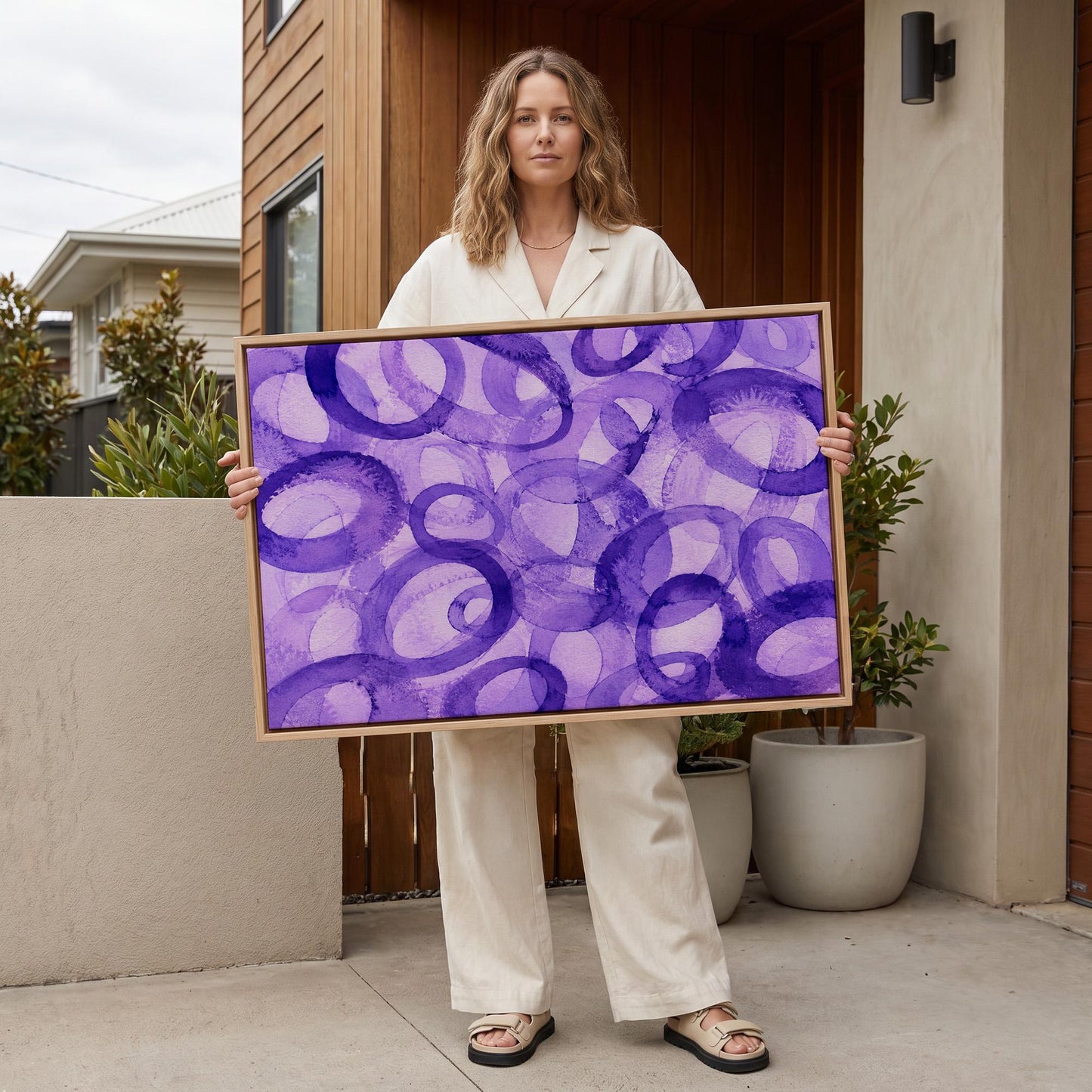 Swirling violet watercolor rings across wide frame, canvas wall art seen in a warm interior with natural light