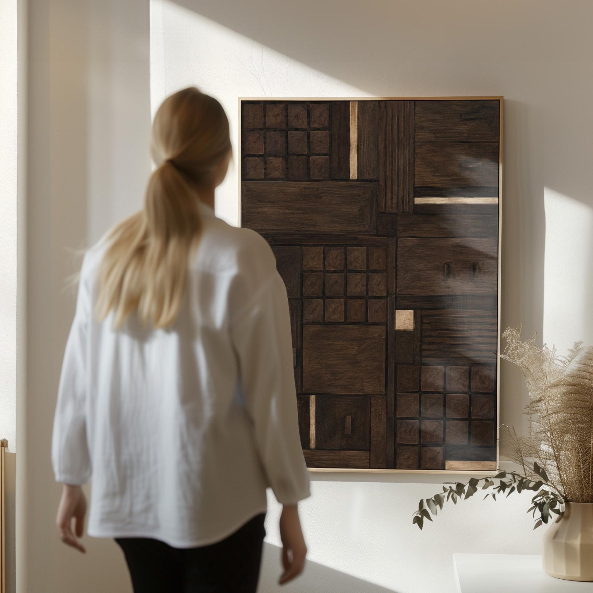 Dark espresso brown geometric patchwork with small gold accents, canvas wall art seen in a warm interior with natural light