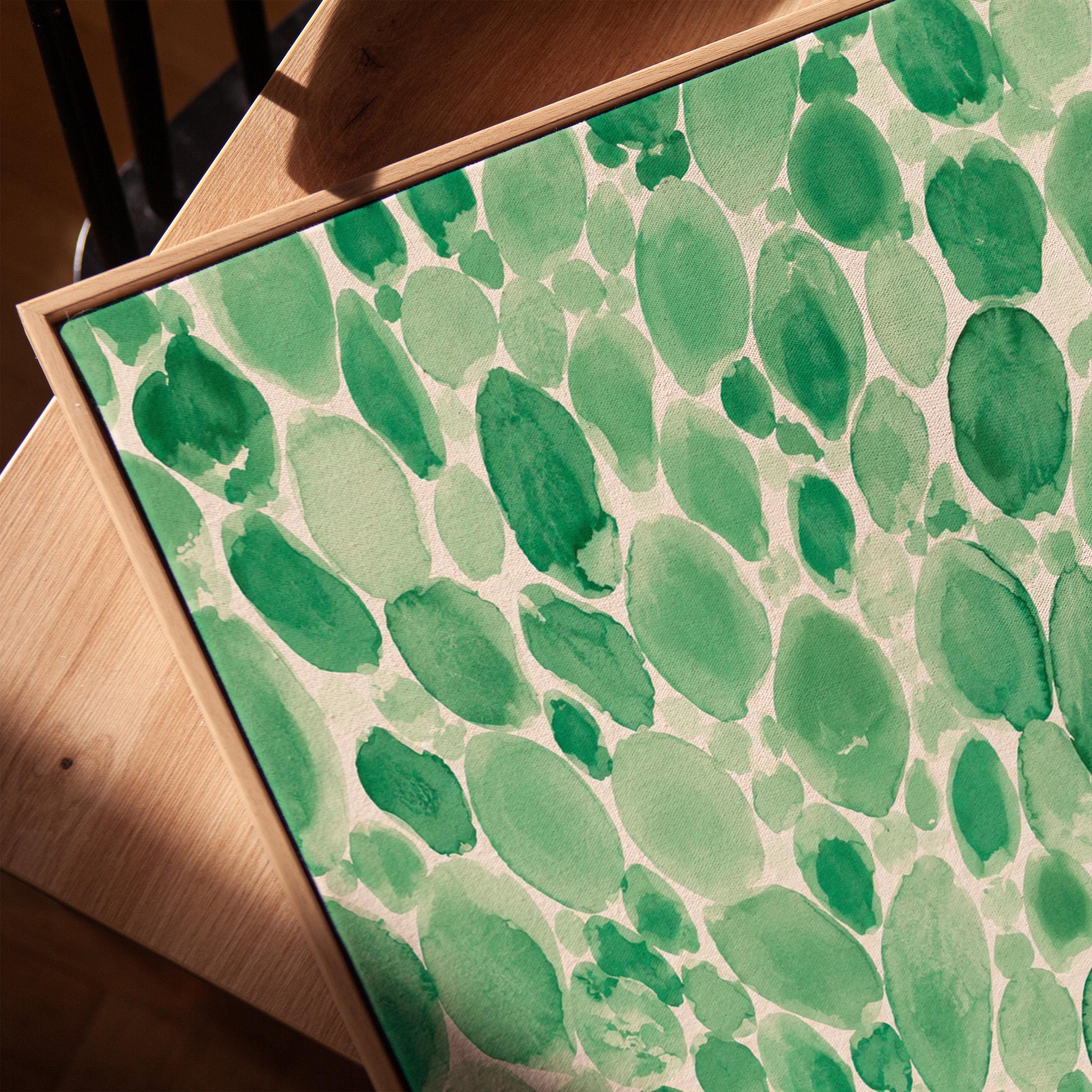 Dense watercolor pebble shapes in mint to emerald green, canvas print in a warm, minimally styled interior
