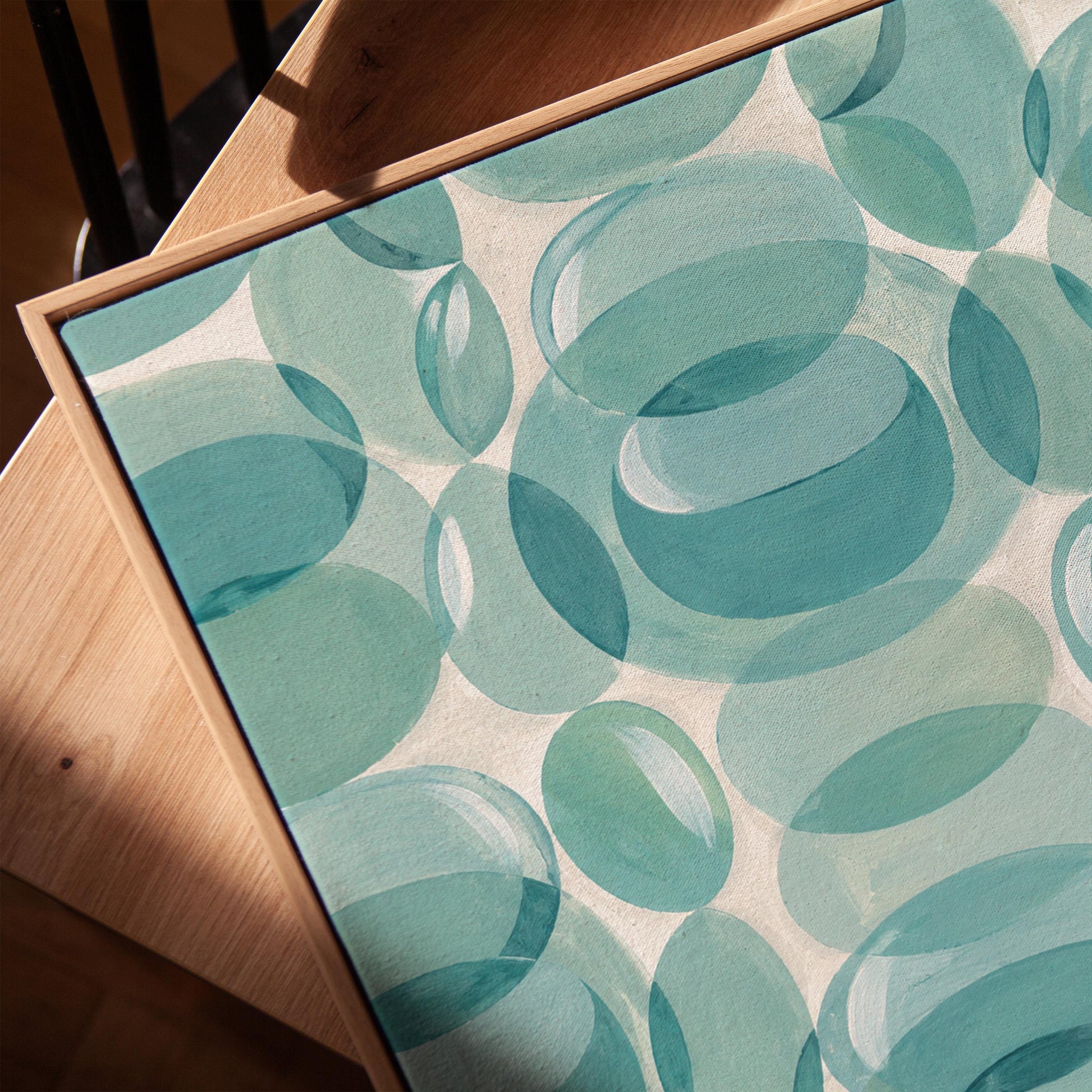Overlapping translucent circles in teal and aqua tones, canvas print in a warm, minimally styled interior