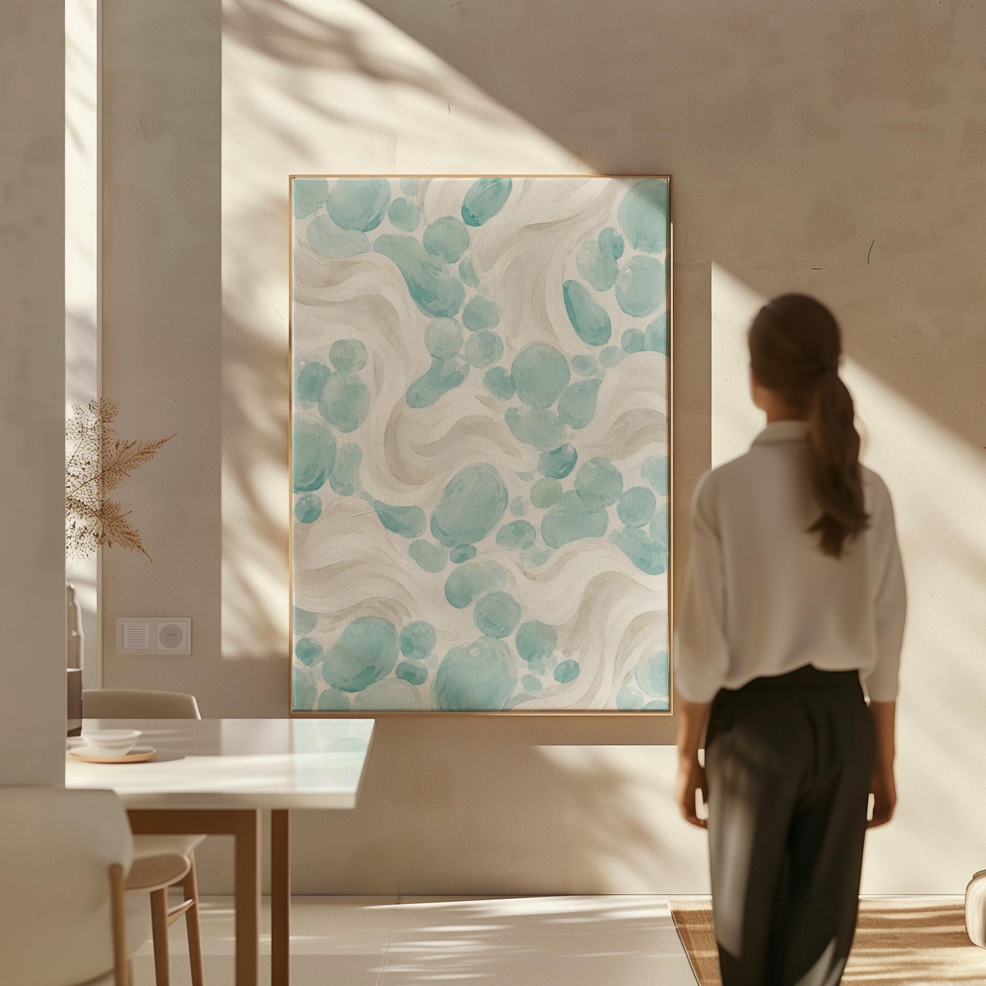 Aqua pebble shapes drifting among soft cream waves, canvas print styled against a soft white wall