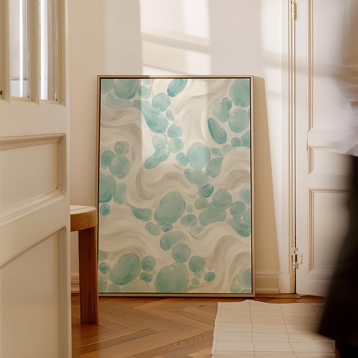 Aqua pebble shapes drifting among soft cream waves, canvas print shown in a sunlit, contemporary room