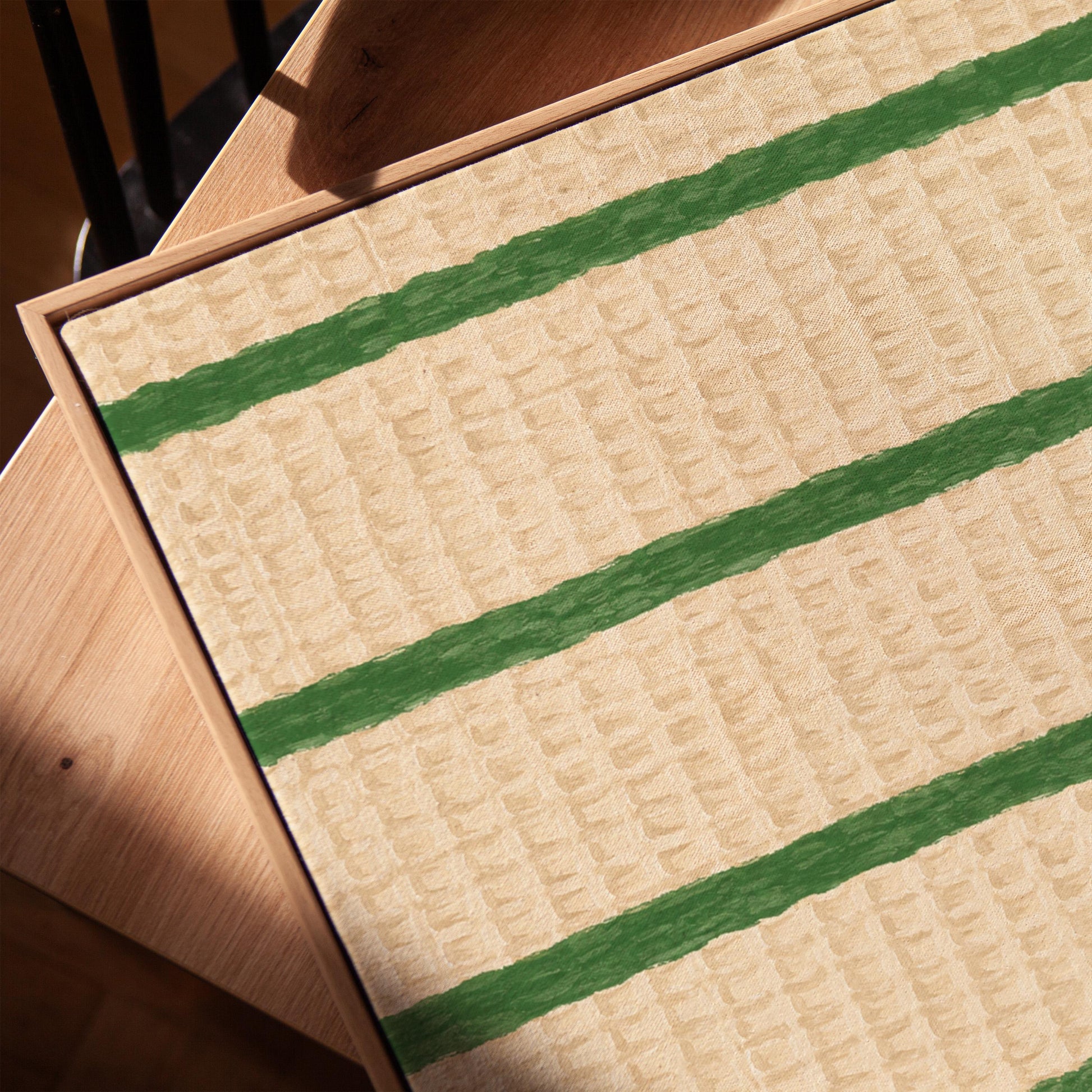 Horizontal grass green stripes on a cream background, canvas print in a warm, minimally styled interior