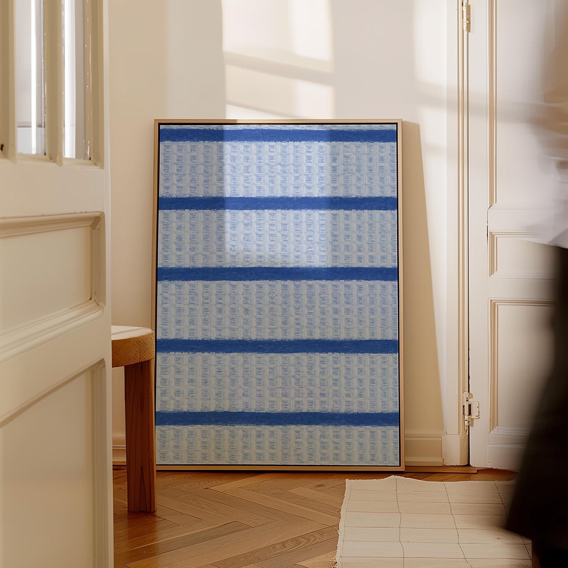 Bold cornflower blue stripes on a pale blue background, canvas wall art on a quiet wall in a considered interior