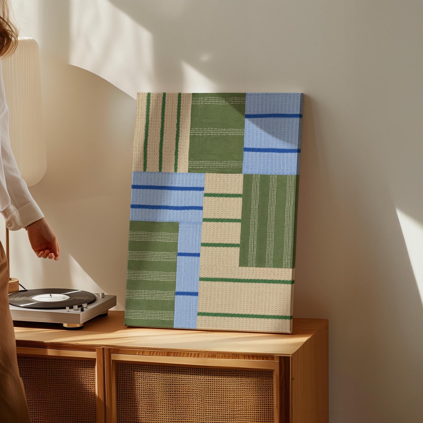 Patchwork of sage green fields with periwinkle blue bands, canvas print presented in a light, minimal room