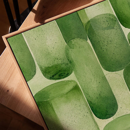 Rounded capsule shapes in layered watercolor greens, canvas print in a warm, minimally styled interior