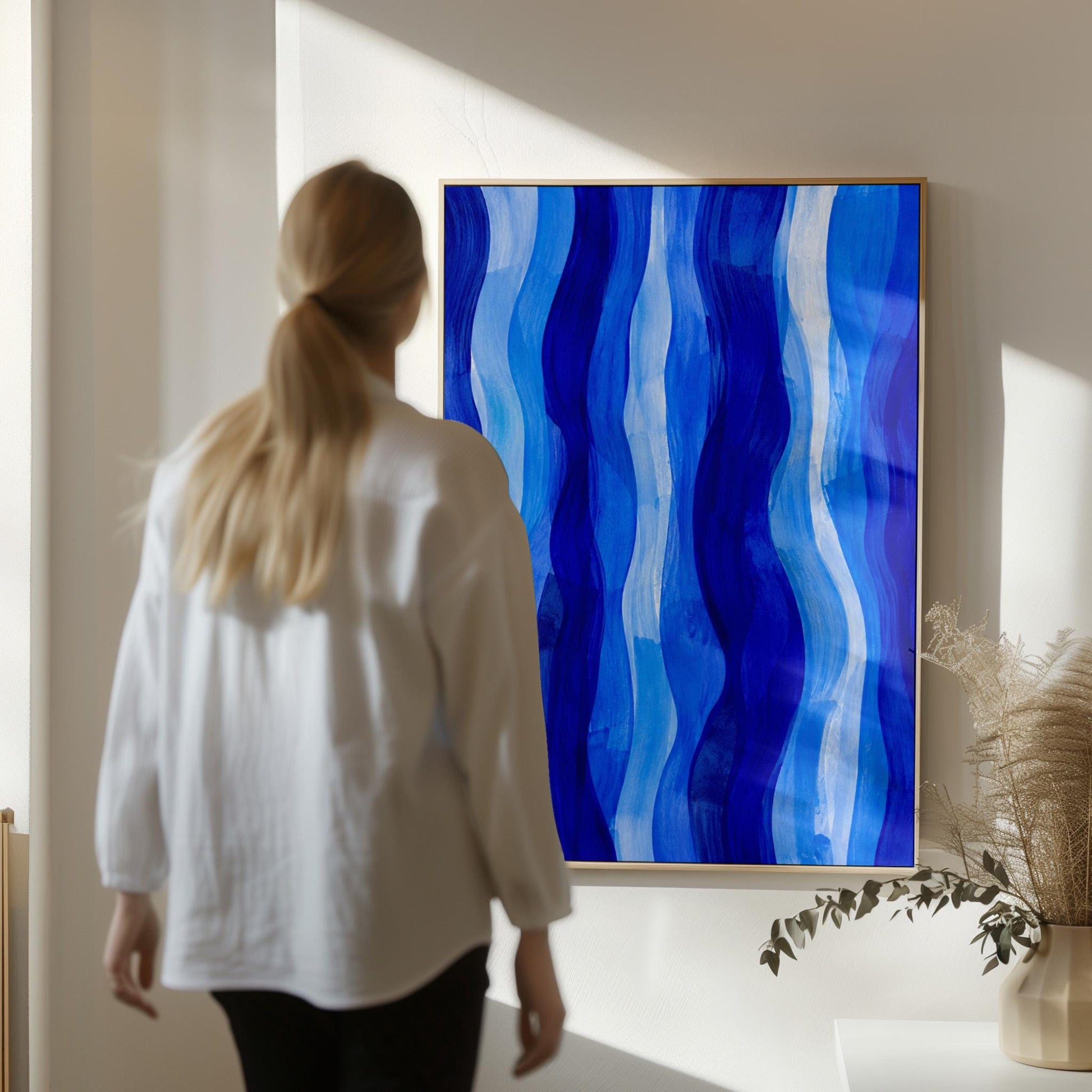 Vertical flowing ribbons in cobalt and light blue, canvas wall art seen in a warm interior with natural light