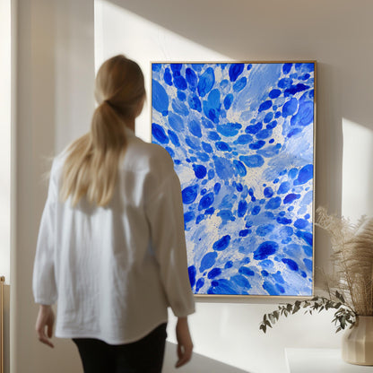 Burst of cobalt blue droplets scattering across pale background, canvas print seen in a warm interior with natural light