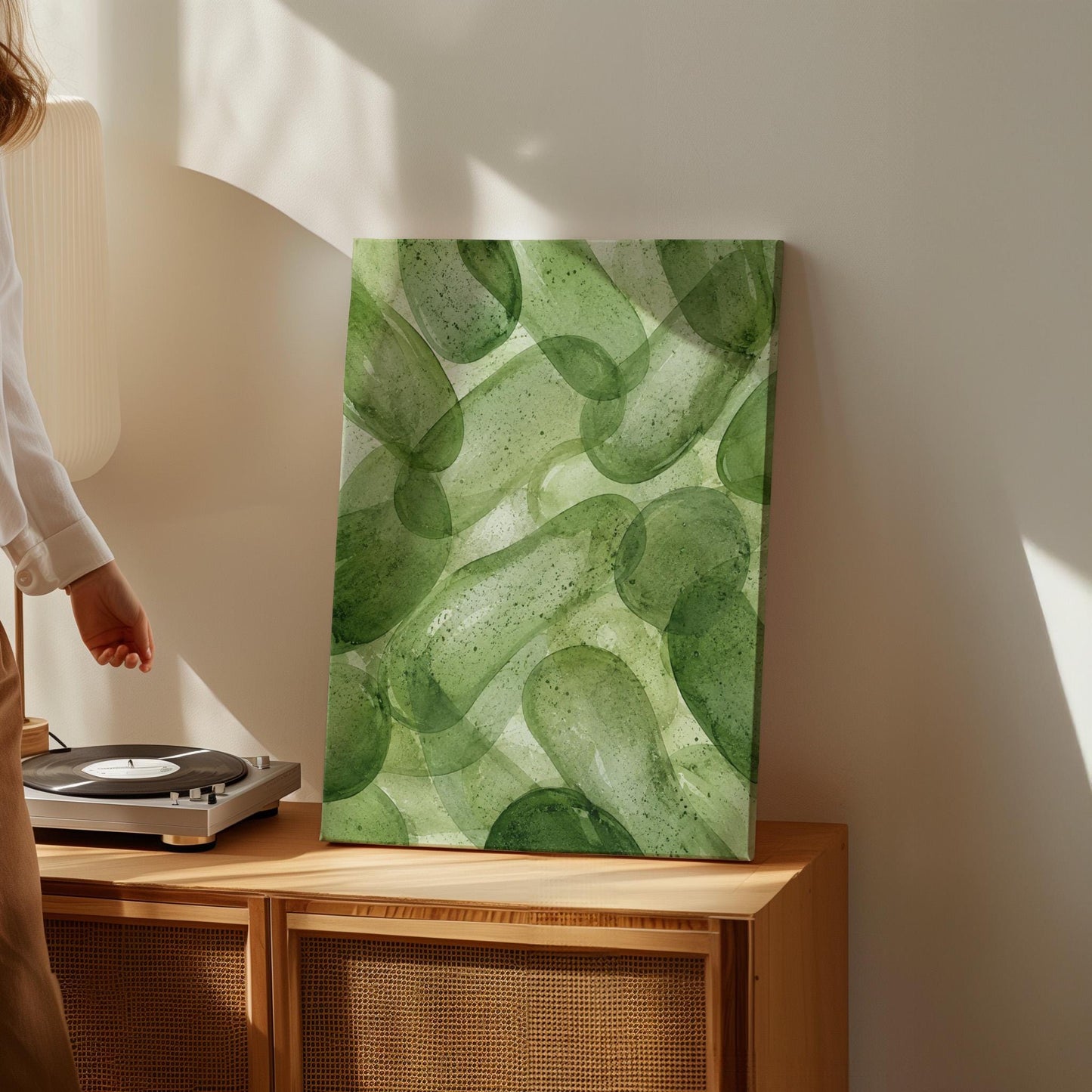 Interlaced looping rings in transparent greens, canvas wall art hanging in a calm, modern living space