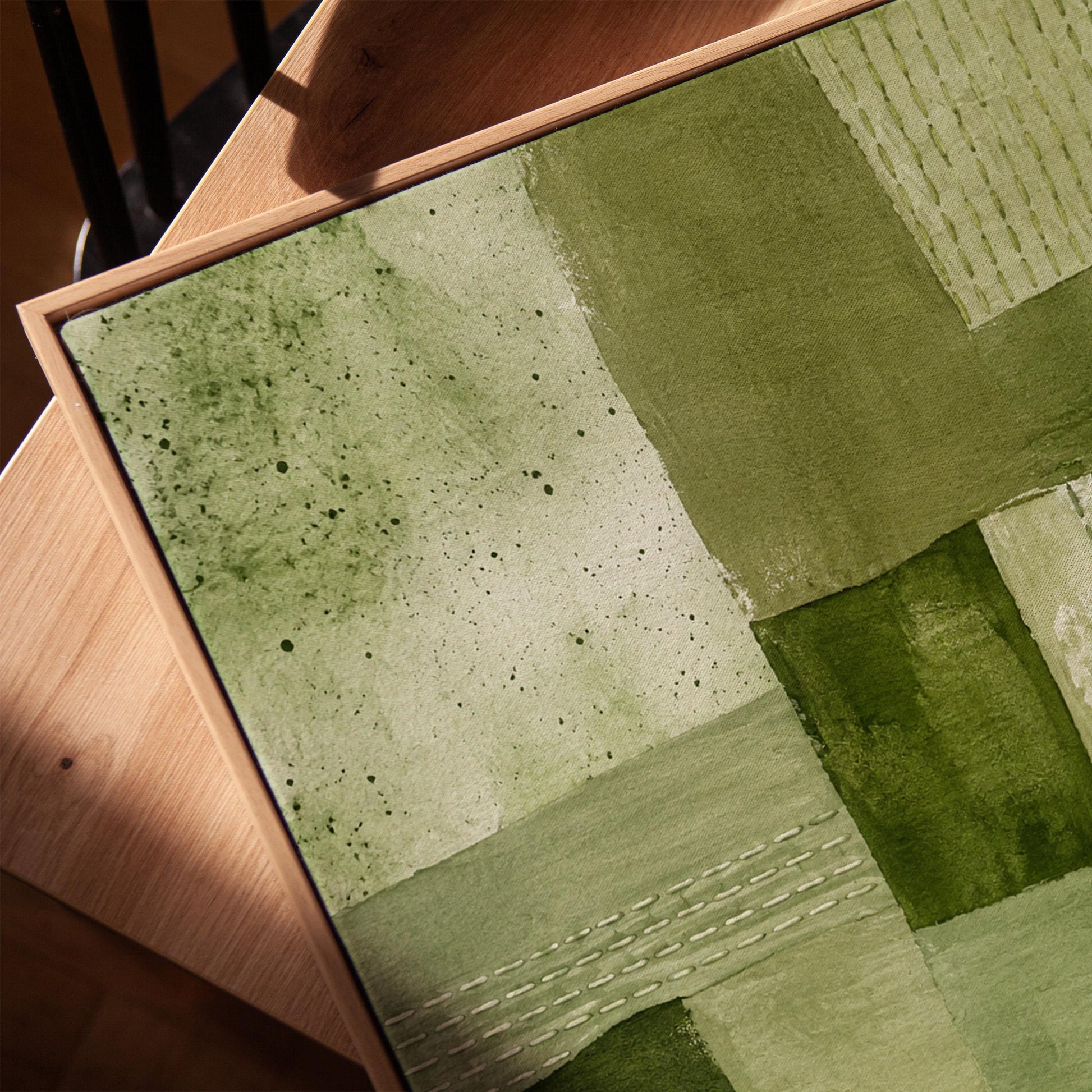 Patchwork of olive and moss green field blocks, canvas print in a warm, minimally styled interior