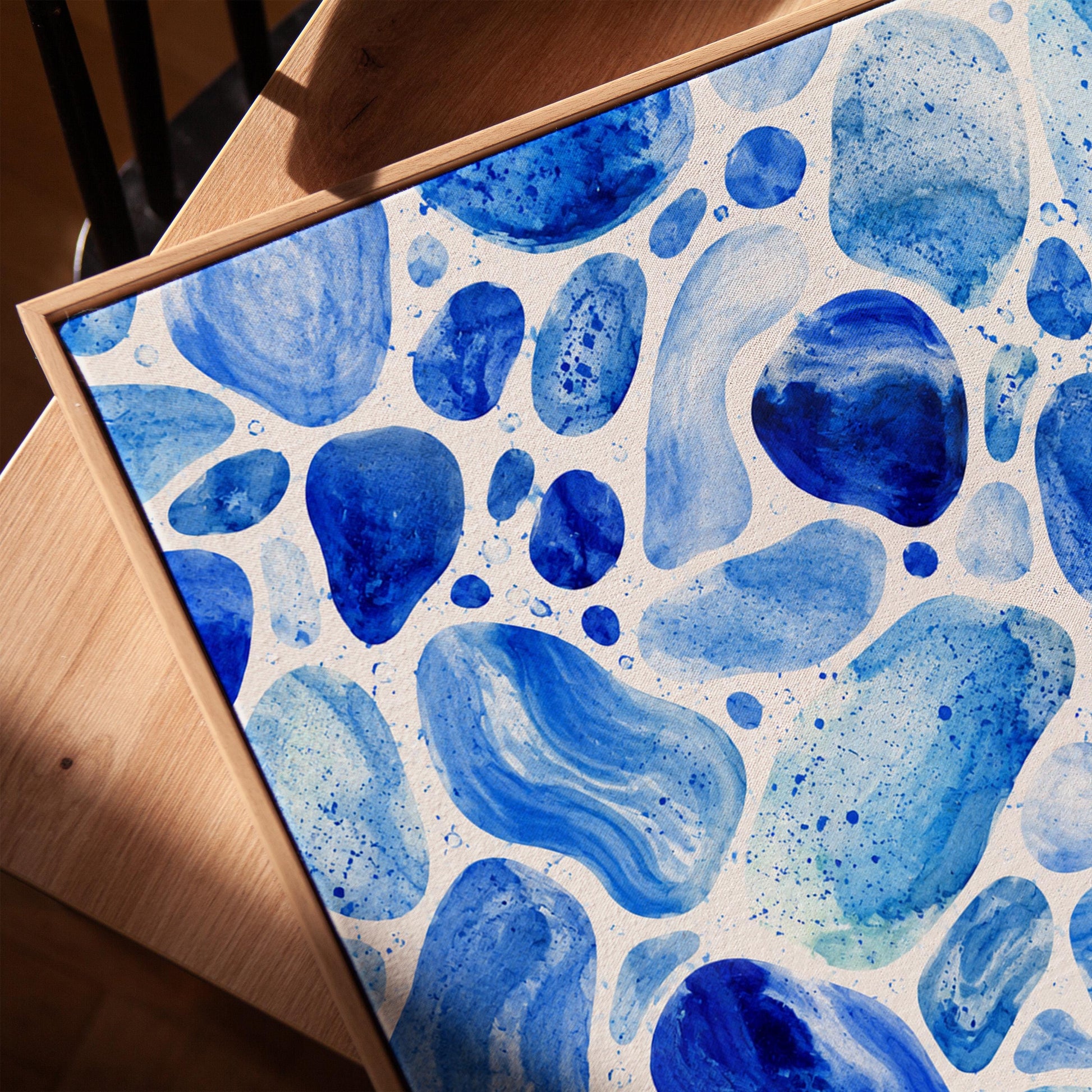 Watercolor pebbles in shades of sky blue and cobalt, canvas print in a warm, minimally styled interior