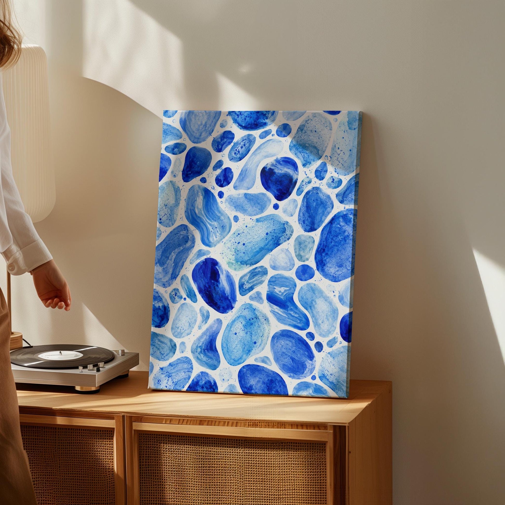 Watercolor pebbles in shades of sky blue and cobalt, canvas print styled against a soft white wall