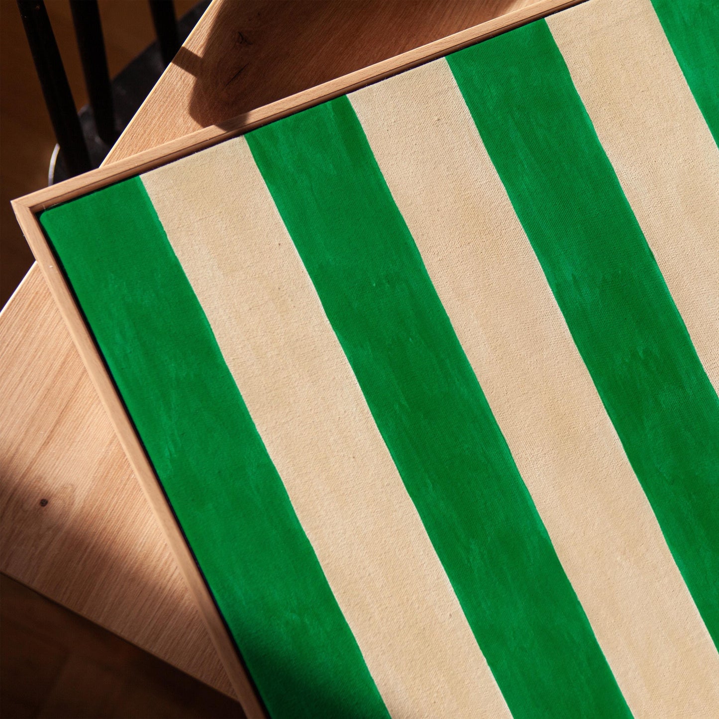 Bold vertical cabana stripes in emerald green and cream, canvas print in a warm, minimally styled interior