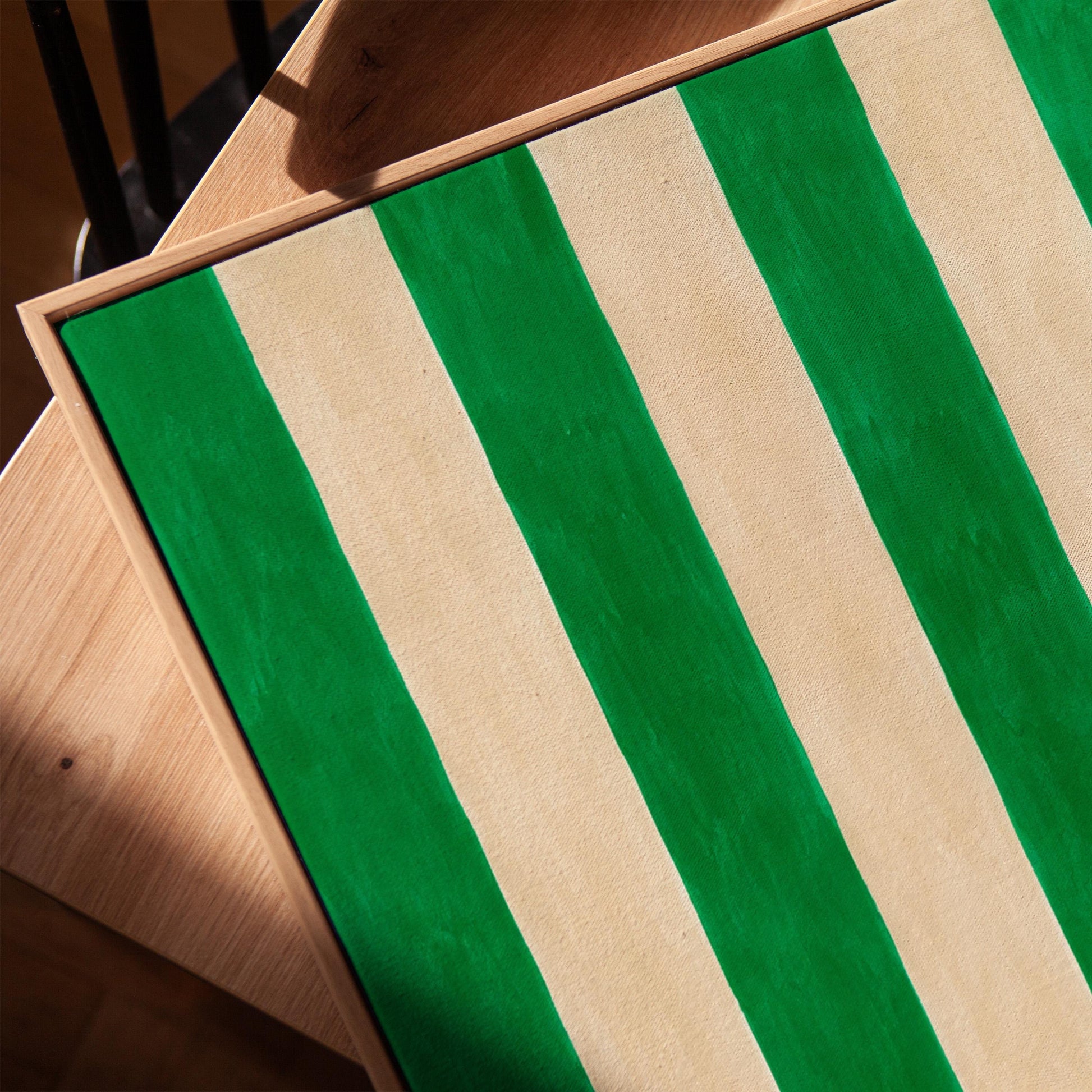 Bold vertical cabana stripes in emerald green and cream, canvas print in a warm, minimally styled interior