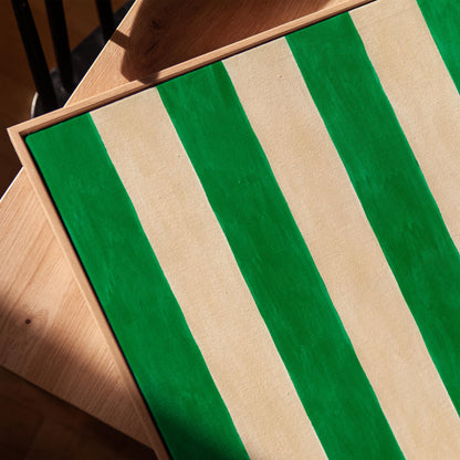 Bold vertical cabana stripes in emerald green and cream, canvas print in a warm, minimally styled interior