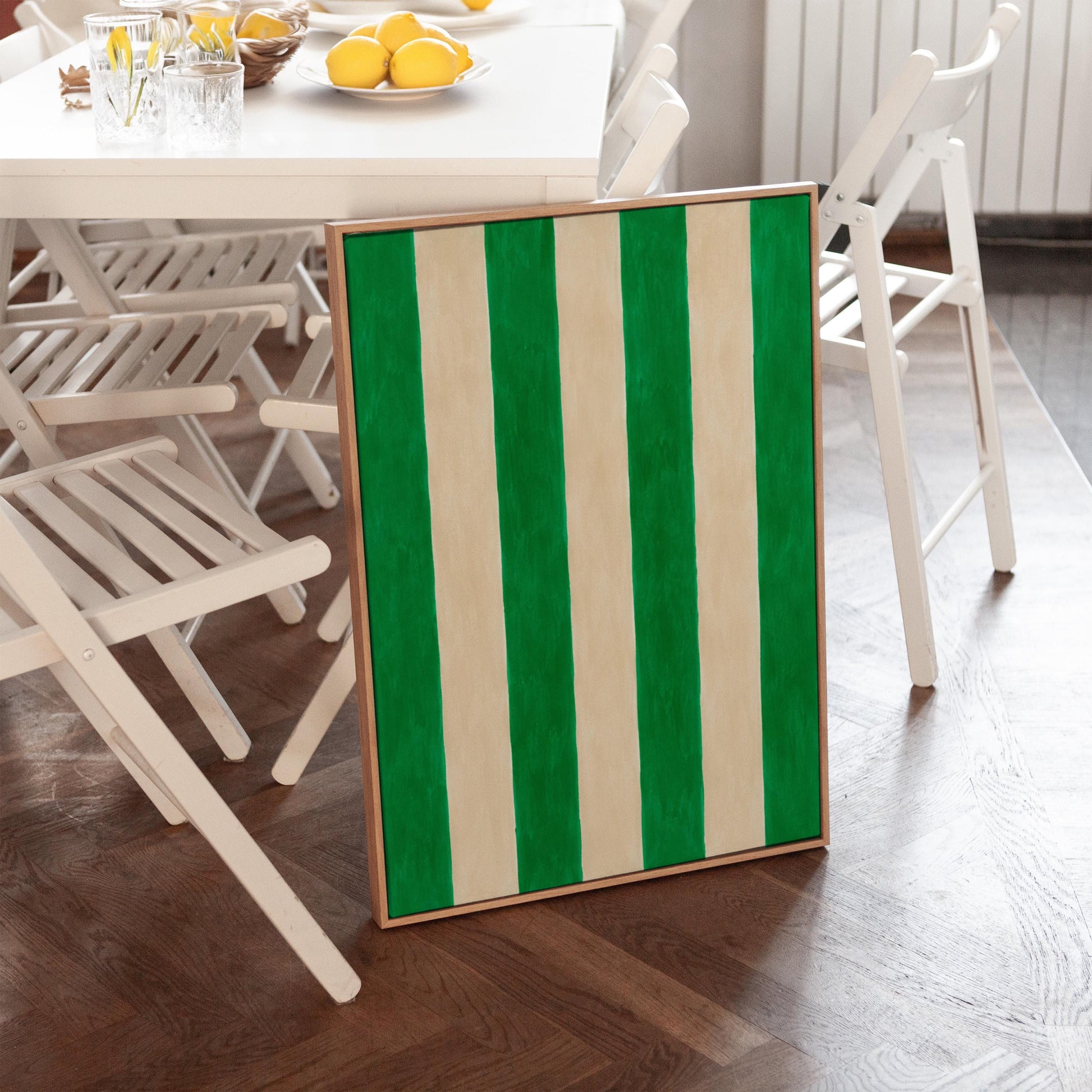 Bold vertical cabana stripes in emerald green and cream, canvas print displayed on a neutral wall in a styled interior