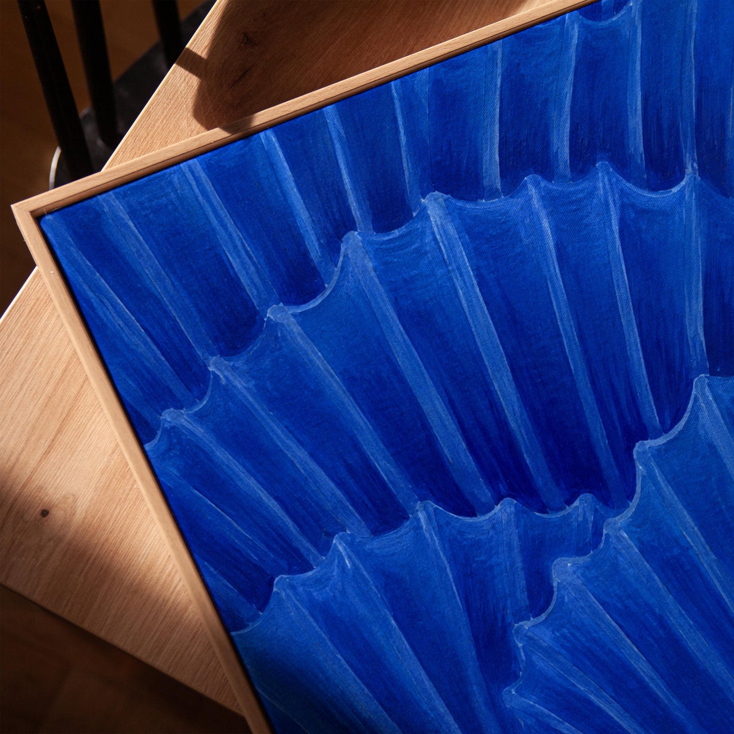Overlapping pleated fan shapes in deep royal blue, canvas print in a warm, minimally styled interior