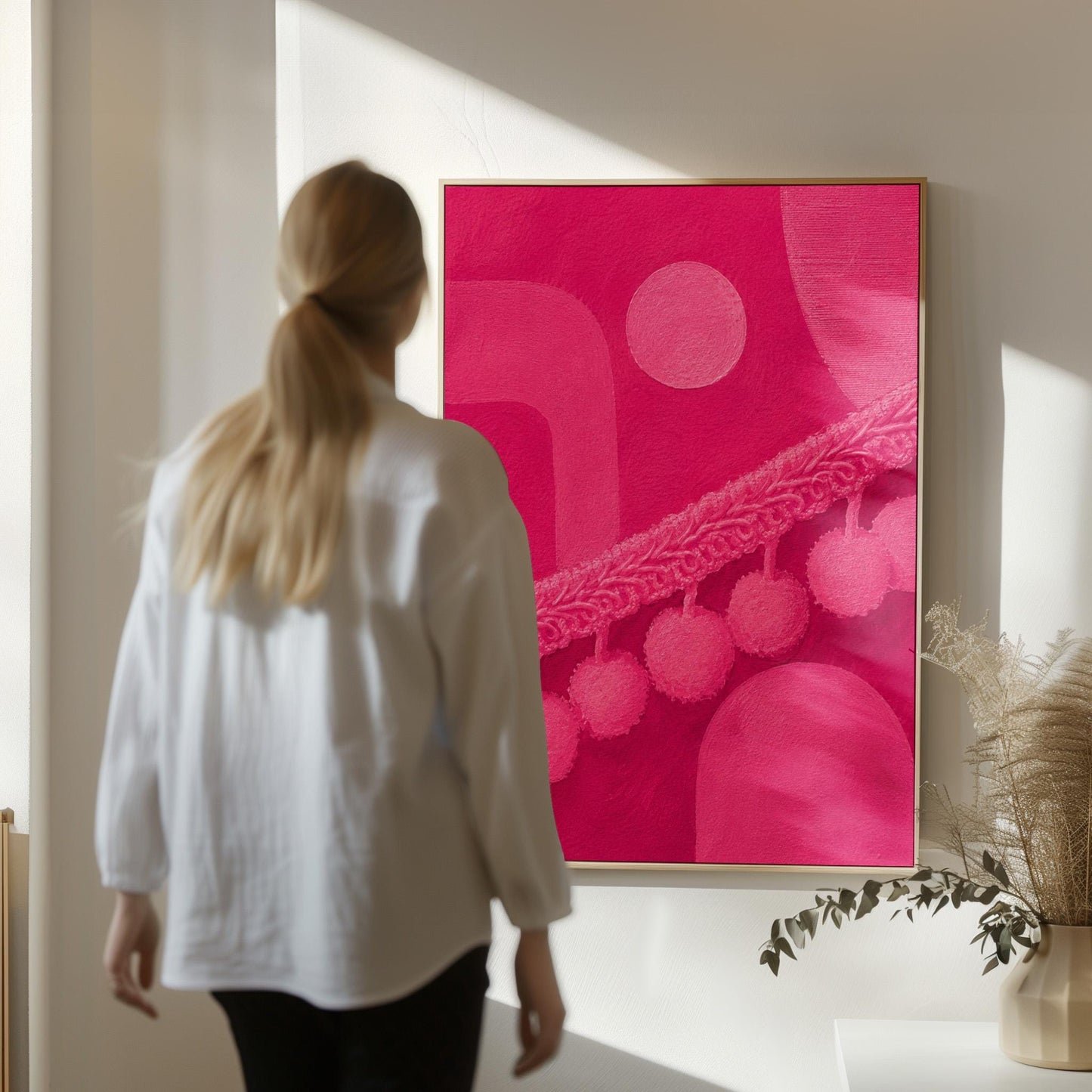 Hot magenta composition with arches and pom pom garland, canvas wall art hanging in a calm, modern living space
