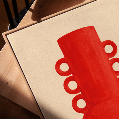 Bold red vessel with ring handles on cream background, canvas print in a warm, minimally styled interior