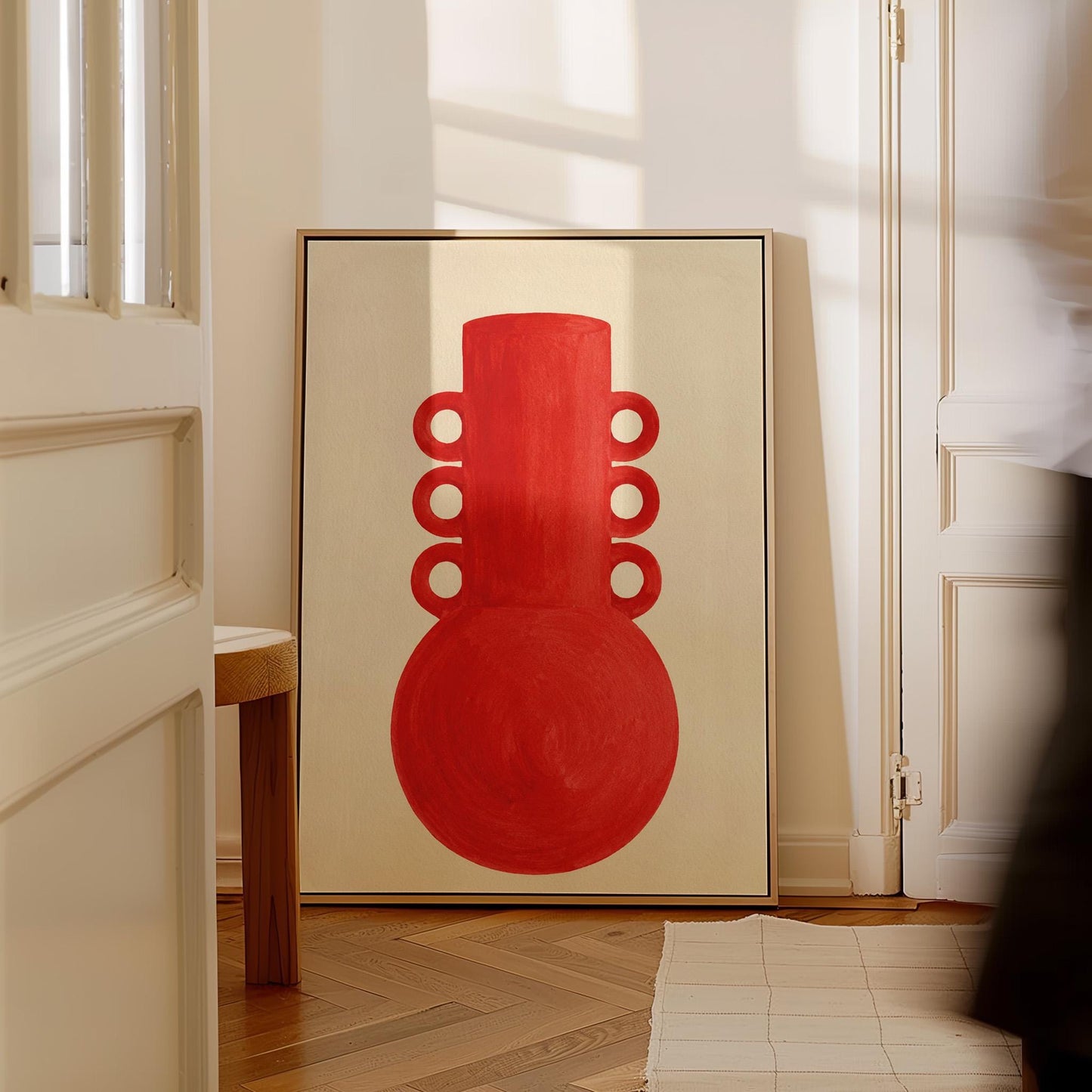 Bold red vessel with ring handles on cream background, canvas print presented in a light, minimal room