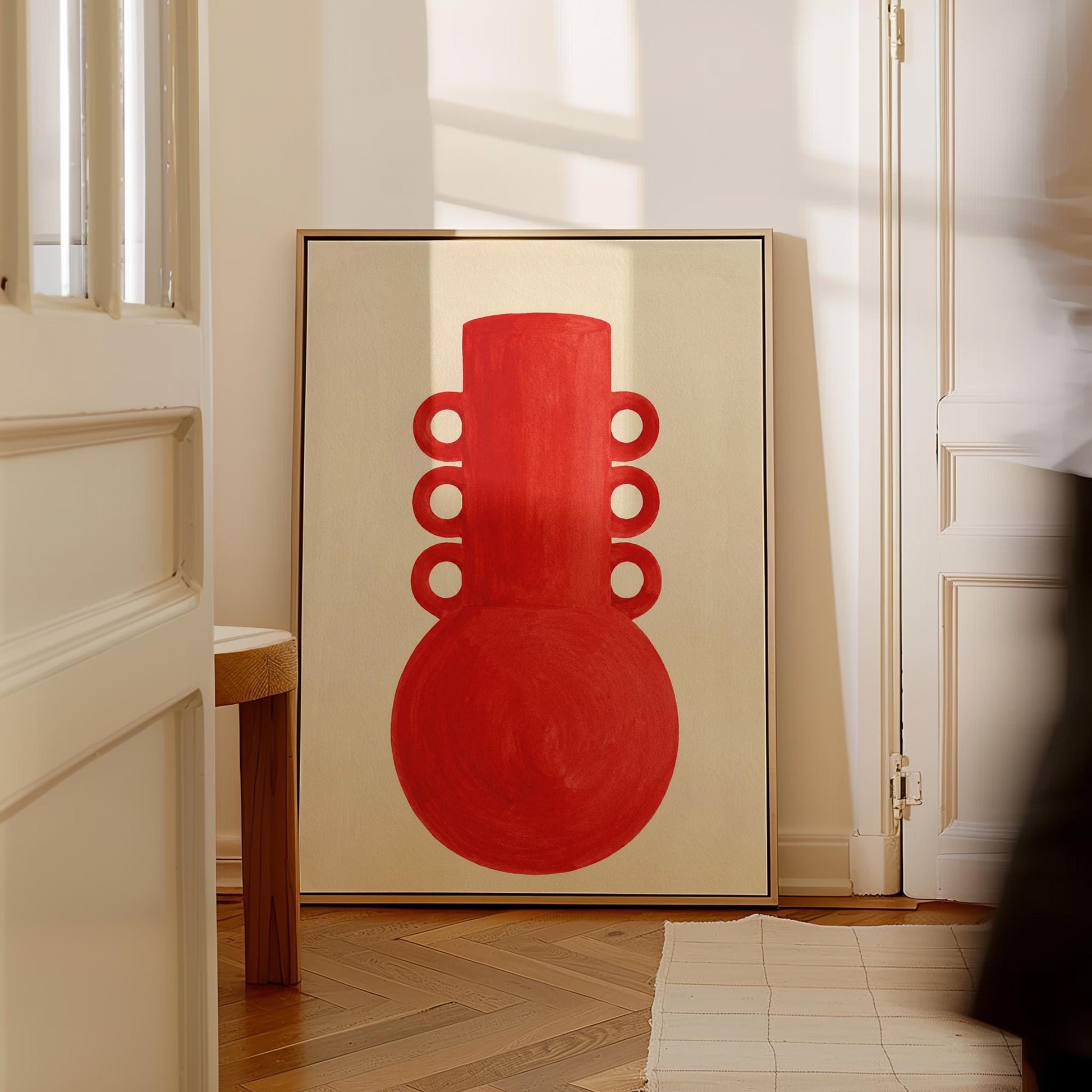 Bold red vessel with ring handles on cream background, canvas print presented in a light, minimal room