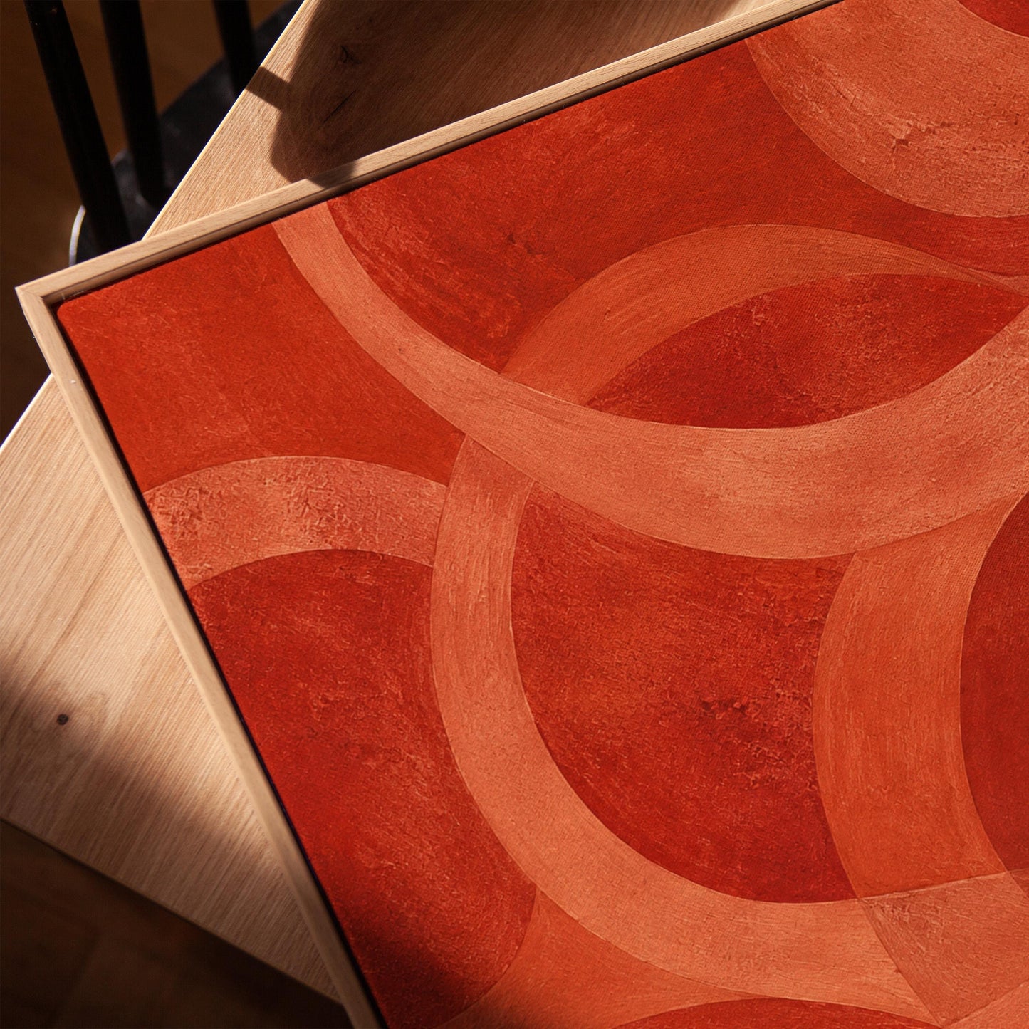 Interlocking loop rings in burnt orange and rust, canvas print in a warm, minimally styled interior