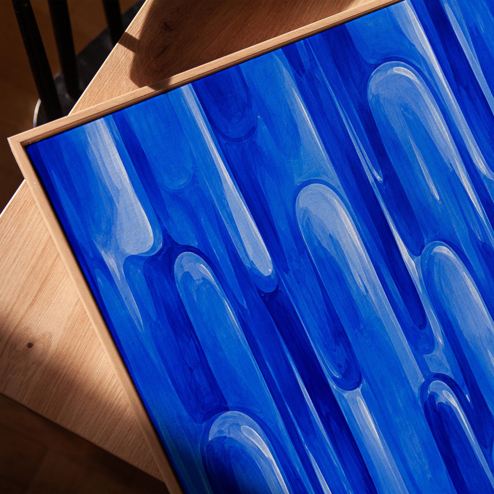 Vertical cobalt streaks like flowing rain, canvas print in a warm, minimally styled interior