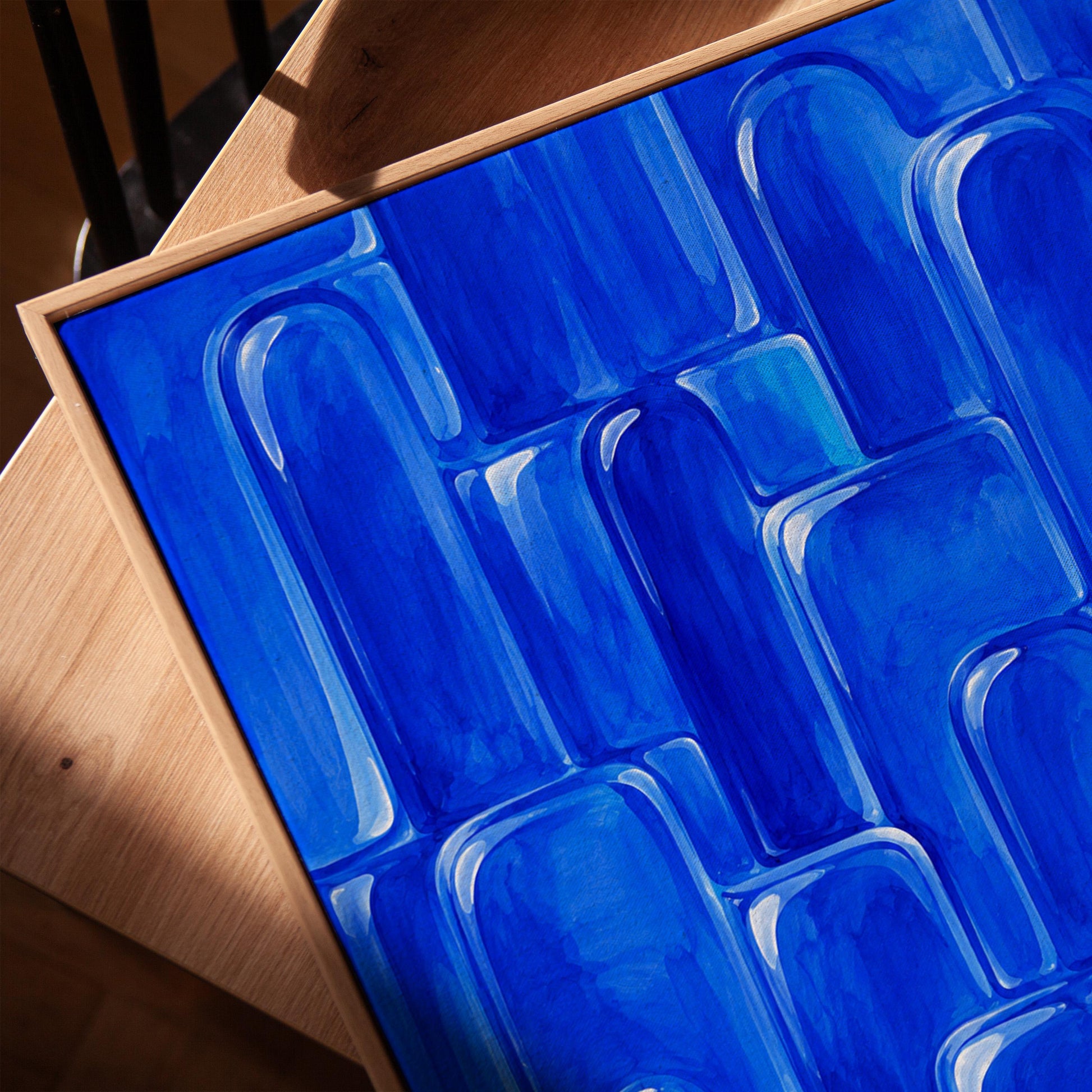 Rounded arch tile shapes in vivid cobalt blue, canvas print in a warm, minimally styled interior