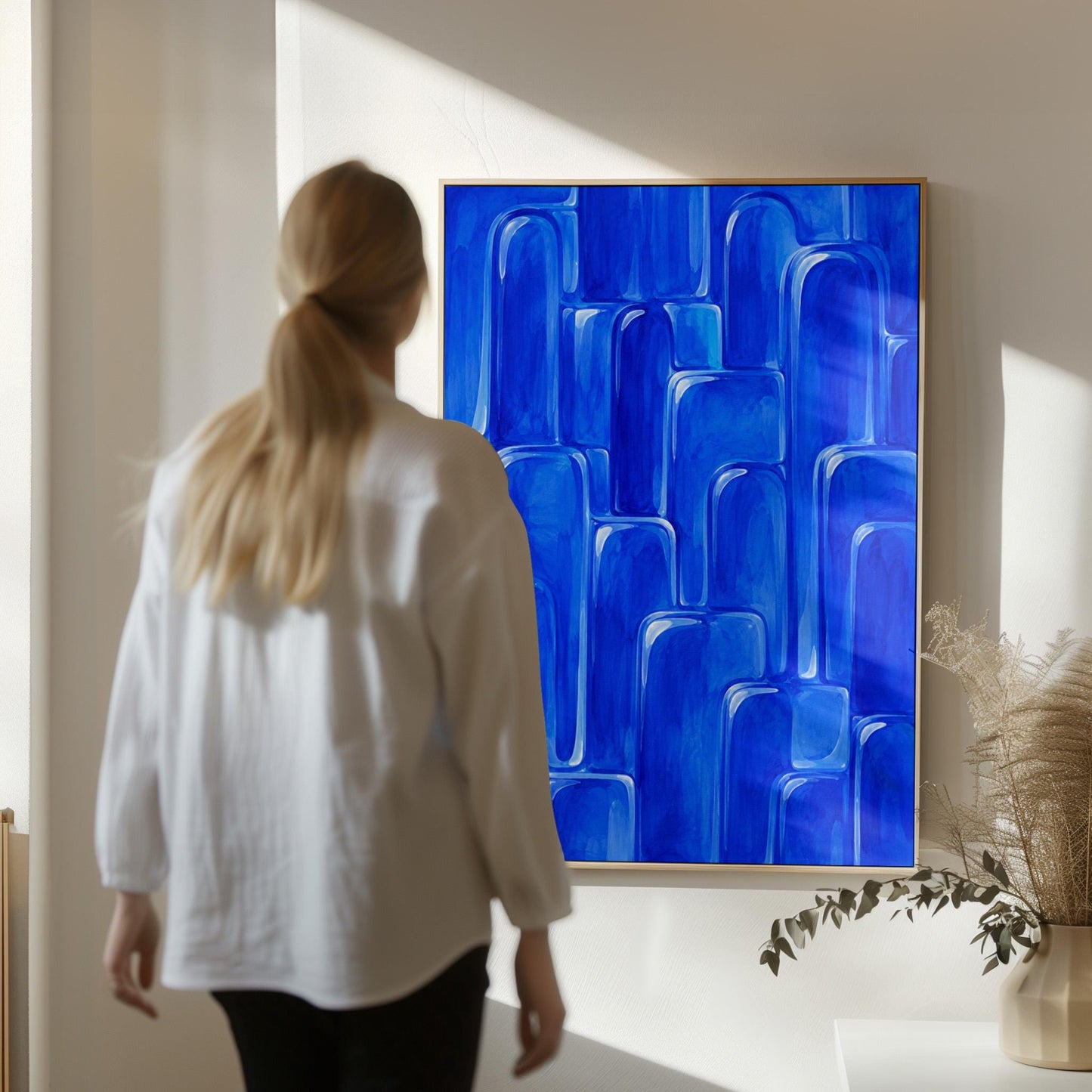 Rounded arch tile shapes in vivid cobalt blue, canvas print displayed on a neutral wall in a styled interior